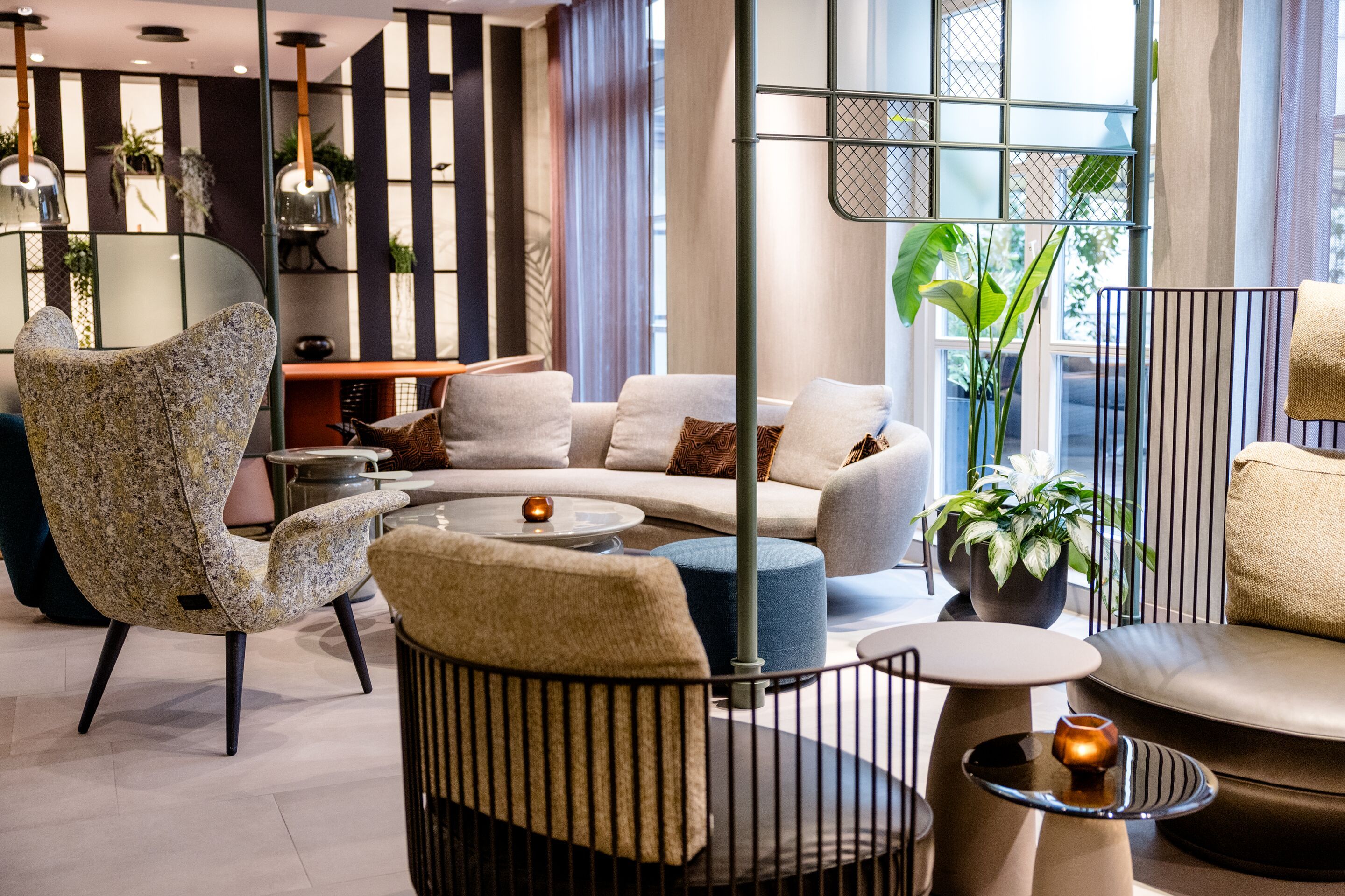 Hotel Frankfurt-Hauptbahnhof Motel One stilvoll eingerichteter Lounge-Bereich mit bequemen Sesseln und Sofas, warmem Licht, dekorativen Pflanzen und gemütlicher Atmosphäre.