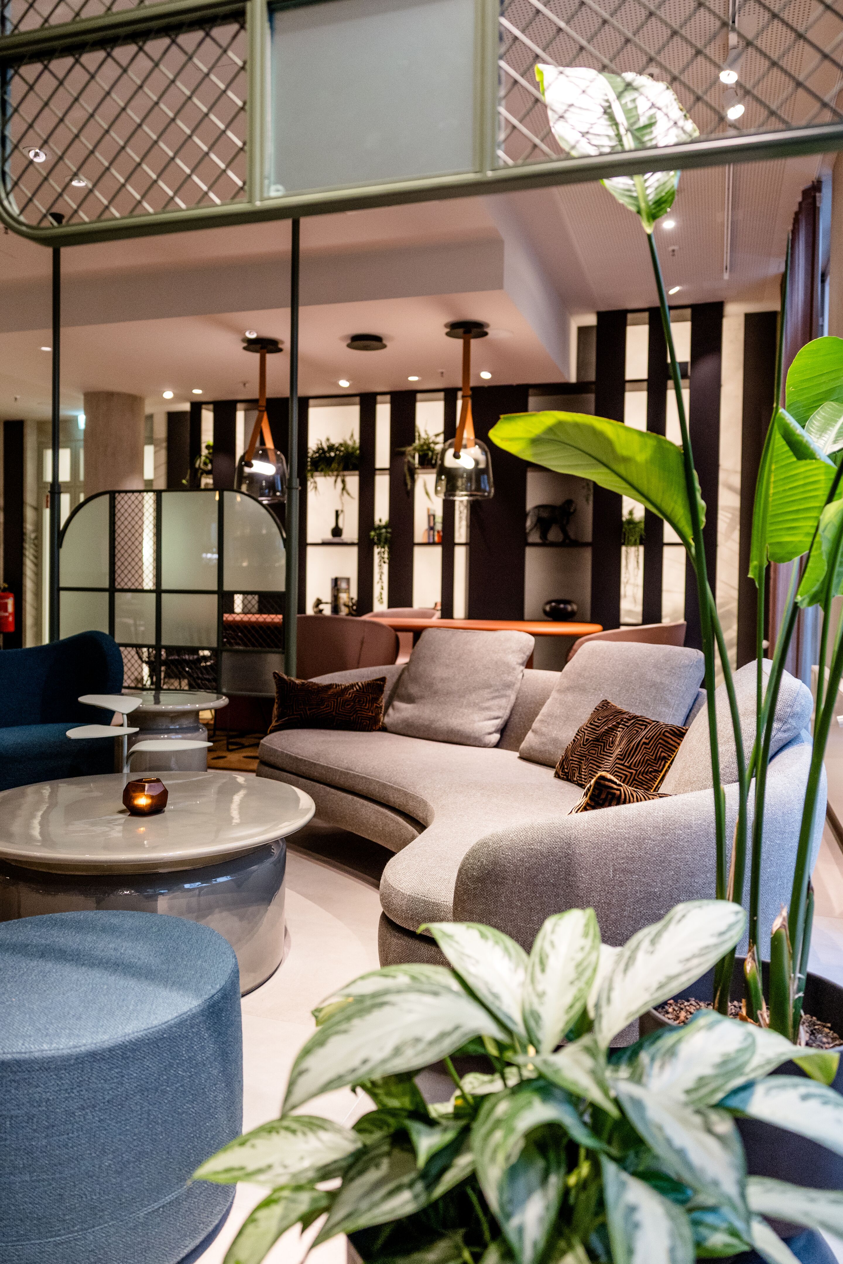 Hotel Frankfurt-Hauptbahnhof Motel One gemütliche Lounge mit geschwungenem Sofa, warmen Lichtakzenten und grünen Pflanzen schafft eine Atmosphäre zum Entspannen und Verweilen.