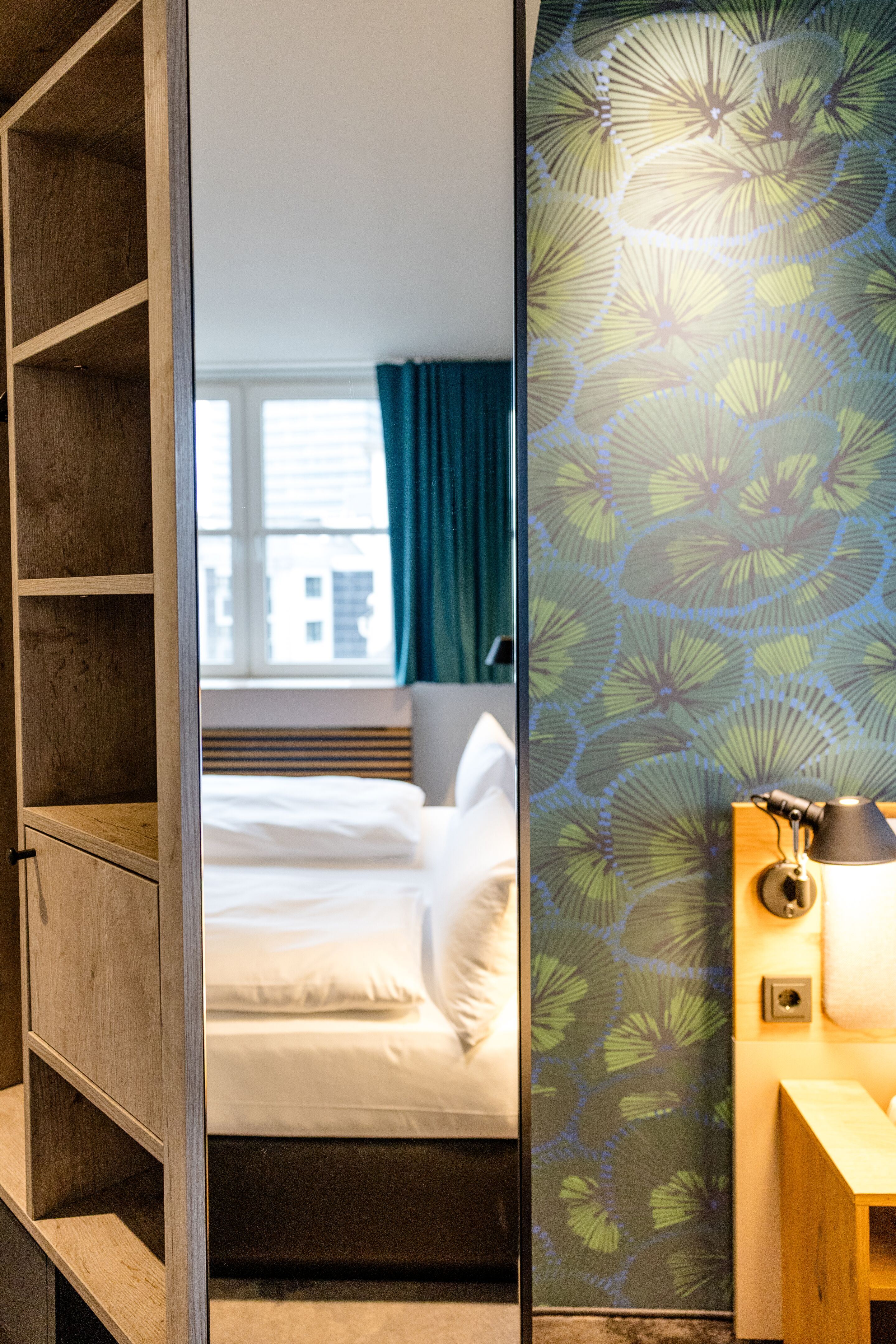 Designhotel Frankfurt Hauptbahnhof Motel One Blick in Hotelzimmer mit hellem Bett, grün-blau gemusterter Wand und indirekter Beleuchtung am Bettkopfbrett. Designhotel Frankfurt Hauptbahnhof Motel One Blick in Hotelzimmer mit hellem Bett, grün-blau gemusterter Wand und indirekter Beleuchtung am Bettkopfbrett.