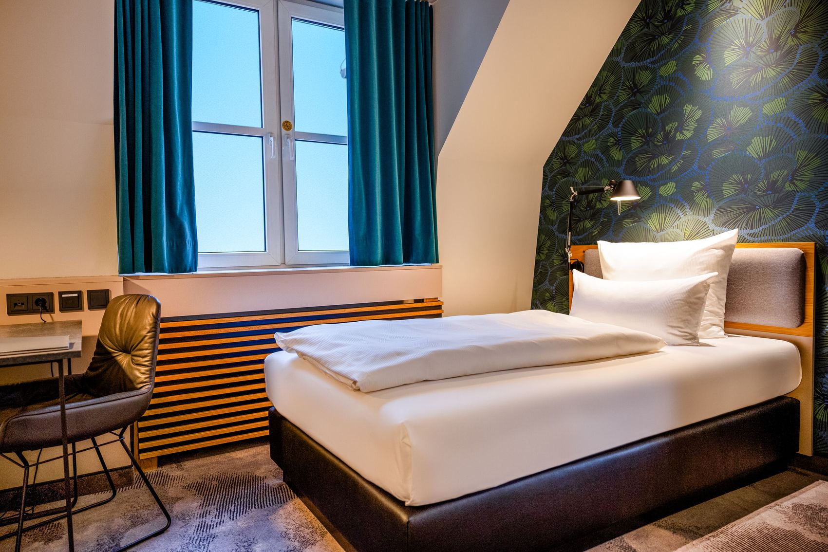 Hotel Motel One Frankfurt-Hauptbahnhof Gemütliches Einzelzimmer mit hochwertigem Bett, sauberen weißen Bettwäsche, stilvoller Tapete und großem Fenster mit Blick nach draußen. Modernes, einladendes Ambiente ideal für entspannte Nächte.