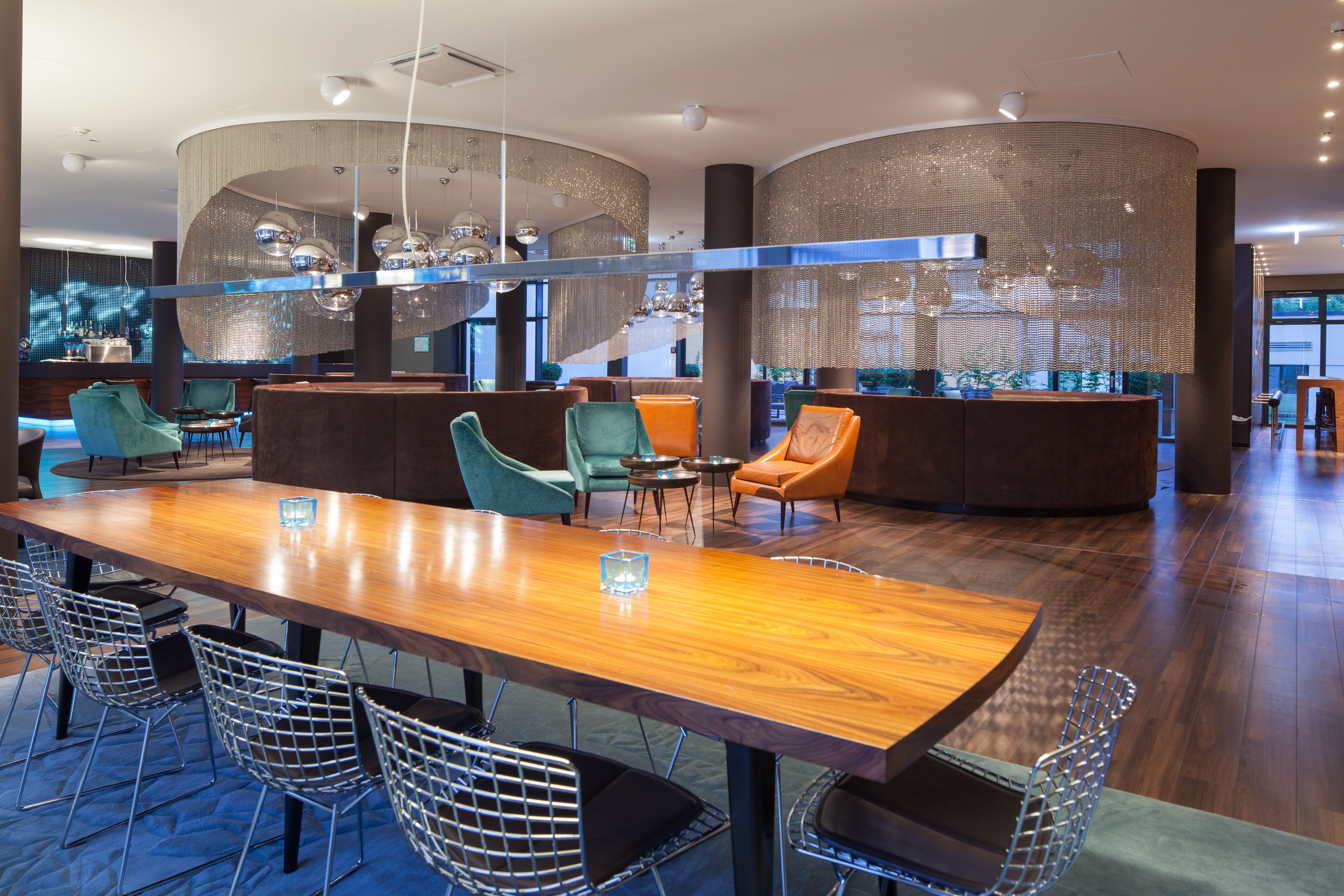Hotel Frankfurt Messe Motel One große Lounge mit Tisch und Stühlen im Vordergrund sowie weiteren Sitzgelegenheiten im Hintergrund