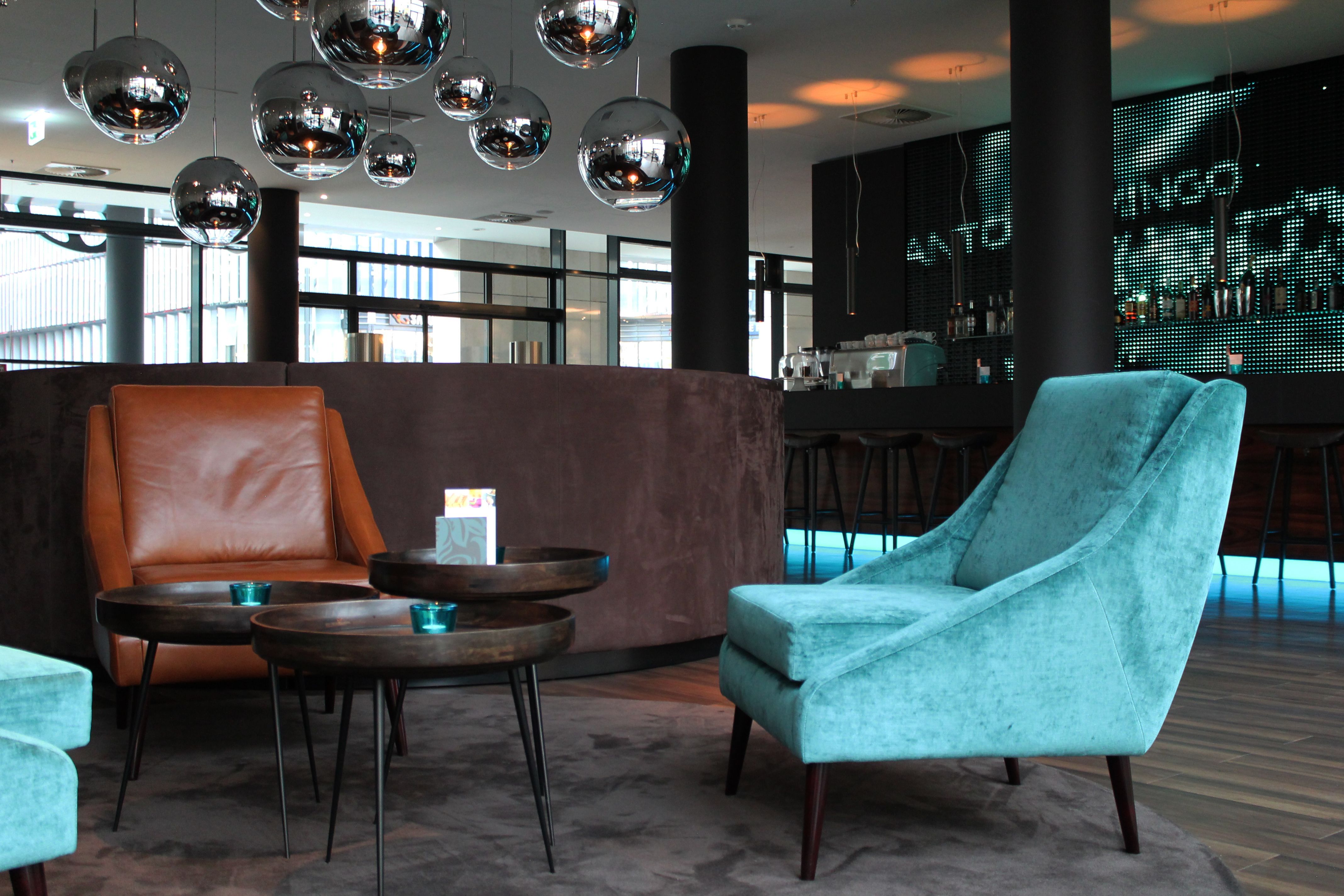 Hotel Frankfurt Messe Motel One Lounge mit Blick auf drei Sessel und Beistelltisch sowie der Bar im Hintergrund