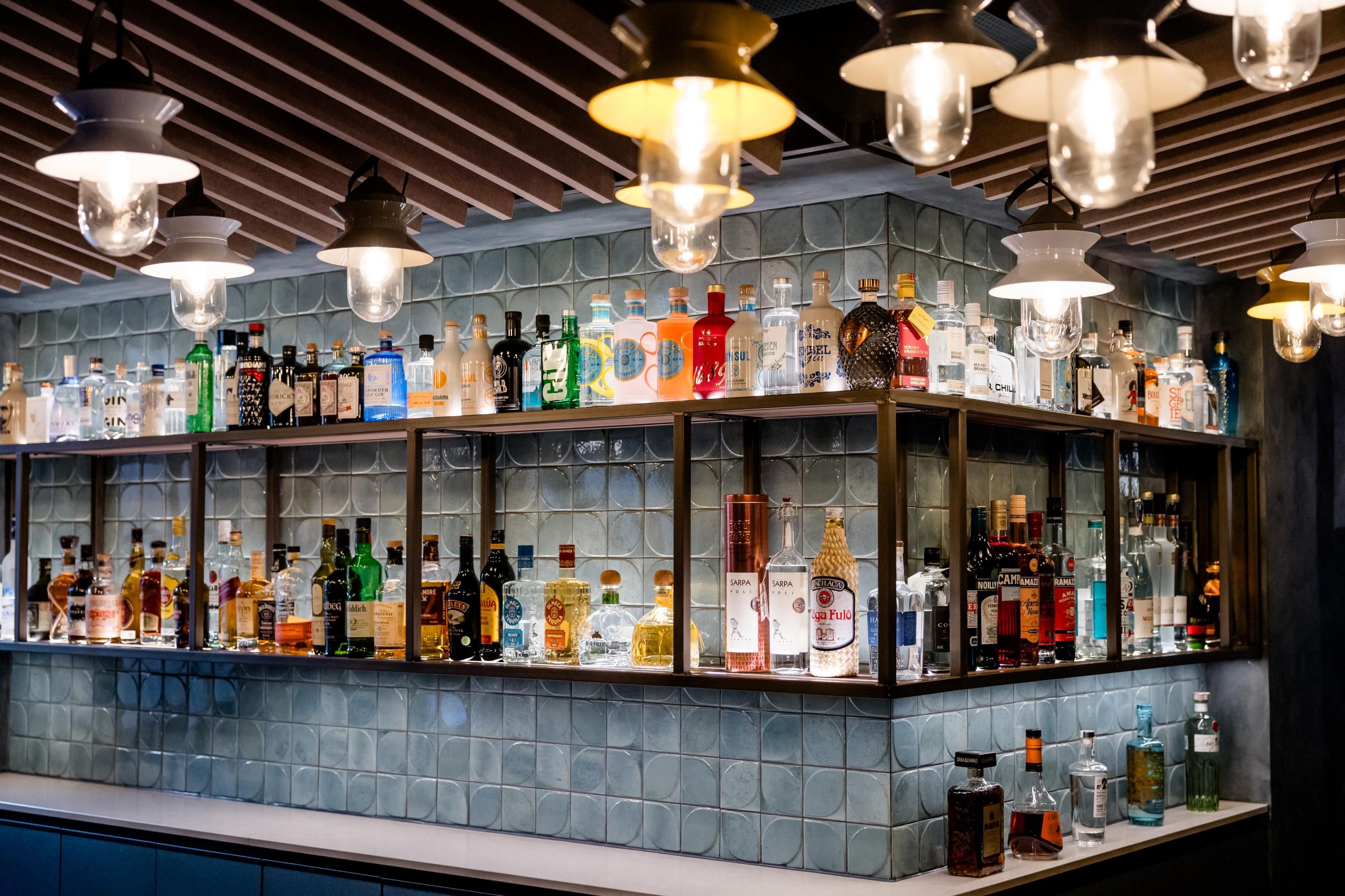 Moderne Hotelbar mit stilvoll beleuchteten Regalen, gefüllt mit einer vielfältigen Auswahl an Spirituosen, um Gästen eine exklusive Atmosphäre für entspannte Abende zu bieten.