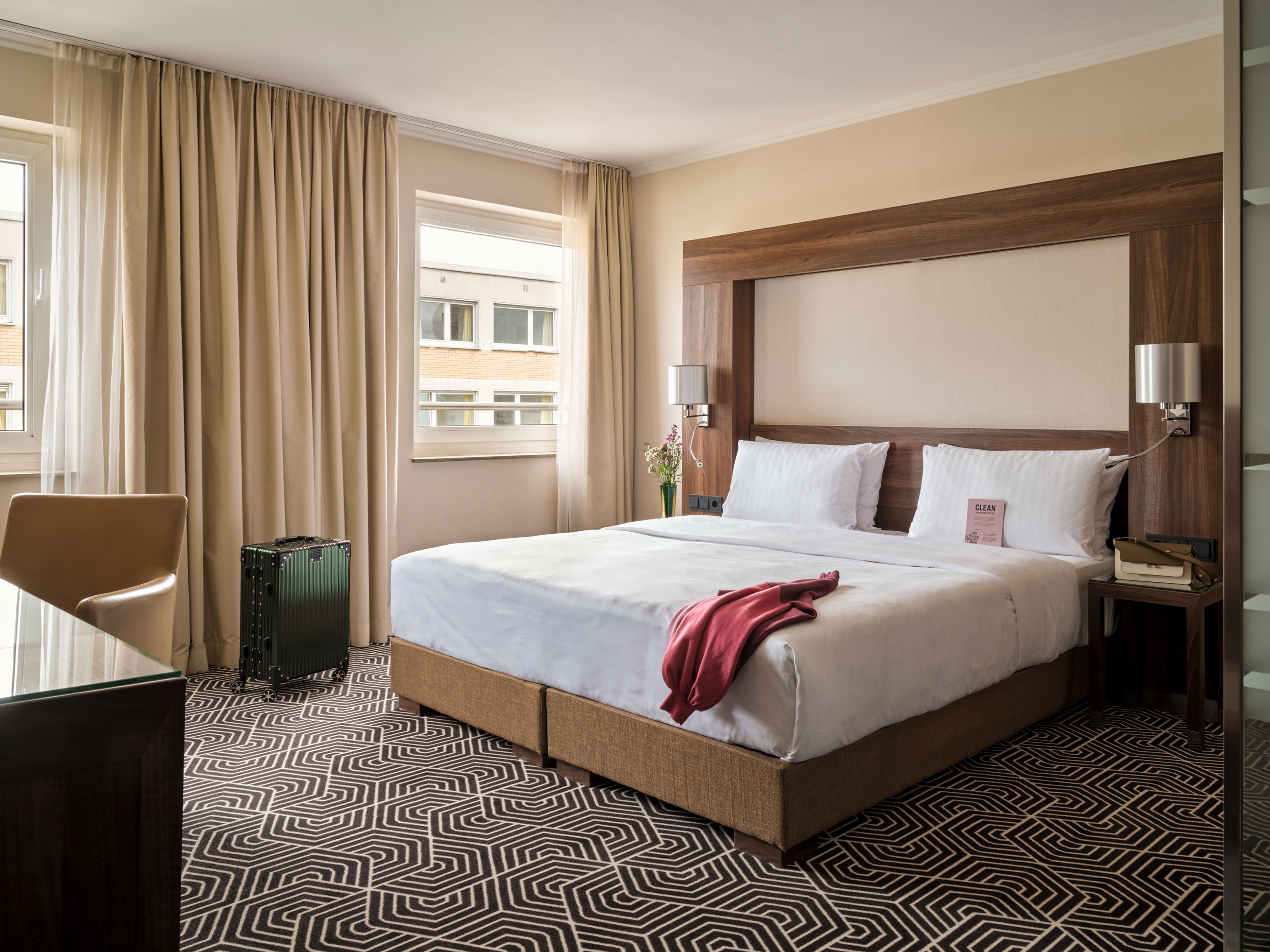 Komfortables Hotelzimmer mit großem Doppelbett, stilvollem Holzrahmen, weichen Vorhängen, Teppichboden in modernem Muster und ruhiger Atmosphäre, ideal für erholsamen Aufenthalt. Komfortables Hotelzimmer mit großem Doppelbett, stilvollem Holzrahmen, weichen Vorhängen, Teppichboden in modernem Muster und ruhiger Atmosphäre, ideal für erholsamen Aufenthalt.