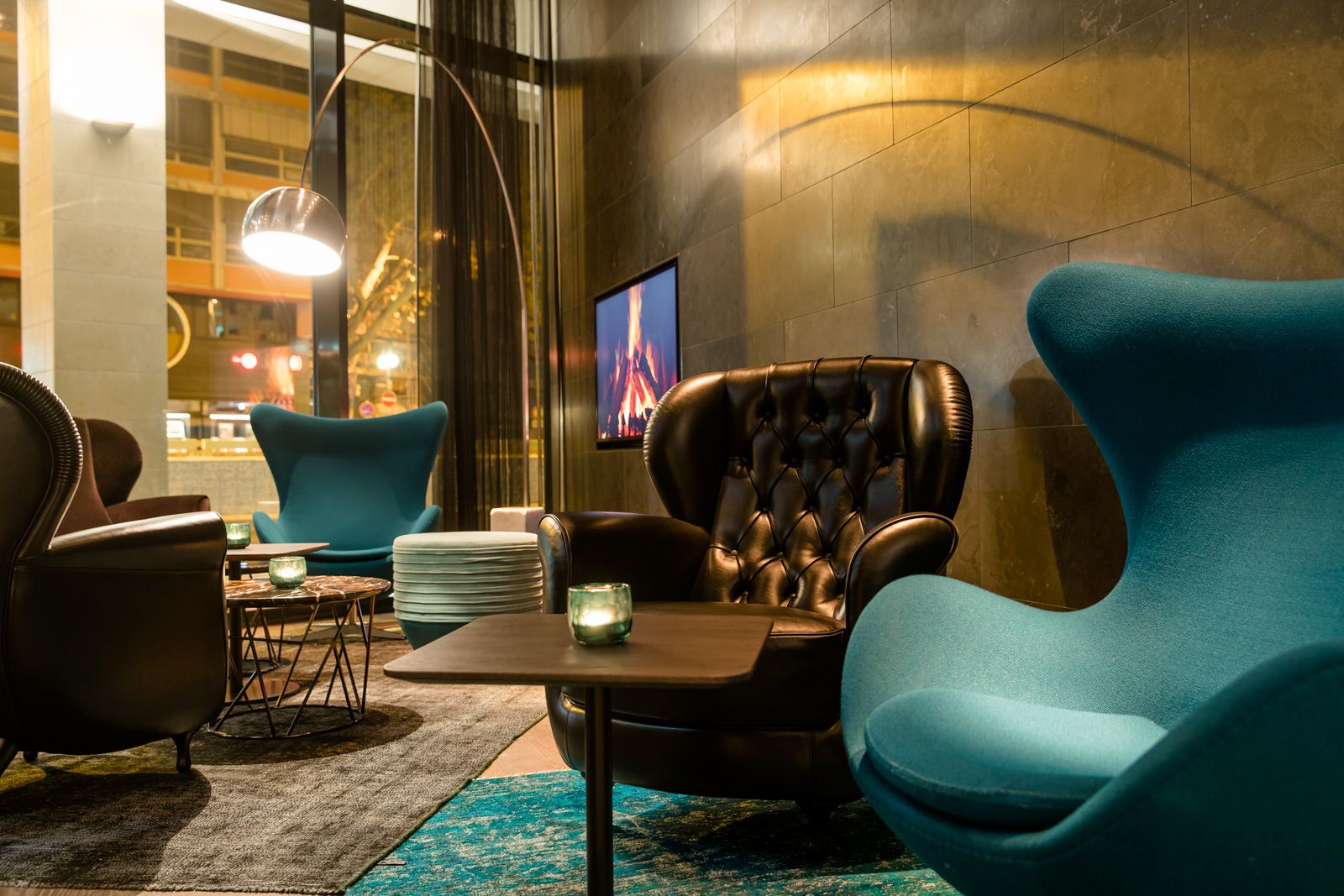 Hotel Frankfurt Römer Motel One Lounge mit Egg chair und weiteren Sesseln sowie einem Fernseher an der Wand