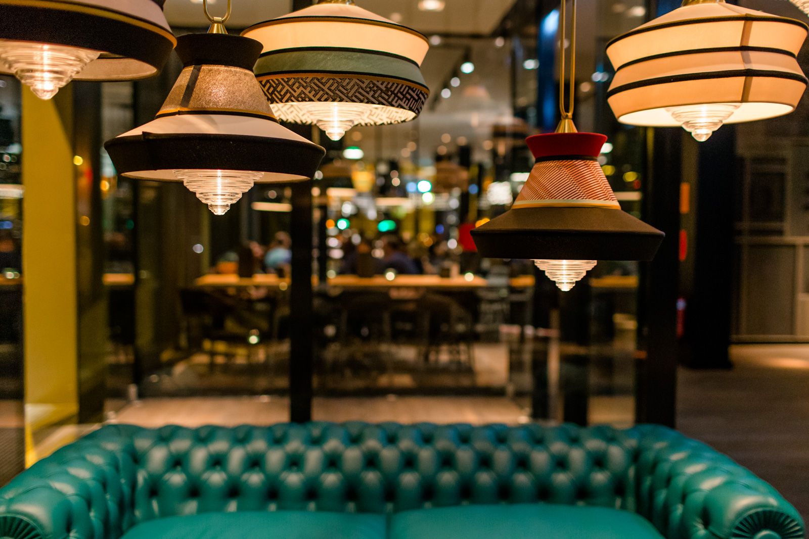 Hotel Frankfurt Römer Motel One Lounge bei Abend mit Blick auf leuchtende Deckenlampen sowie eine komfortable Couch