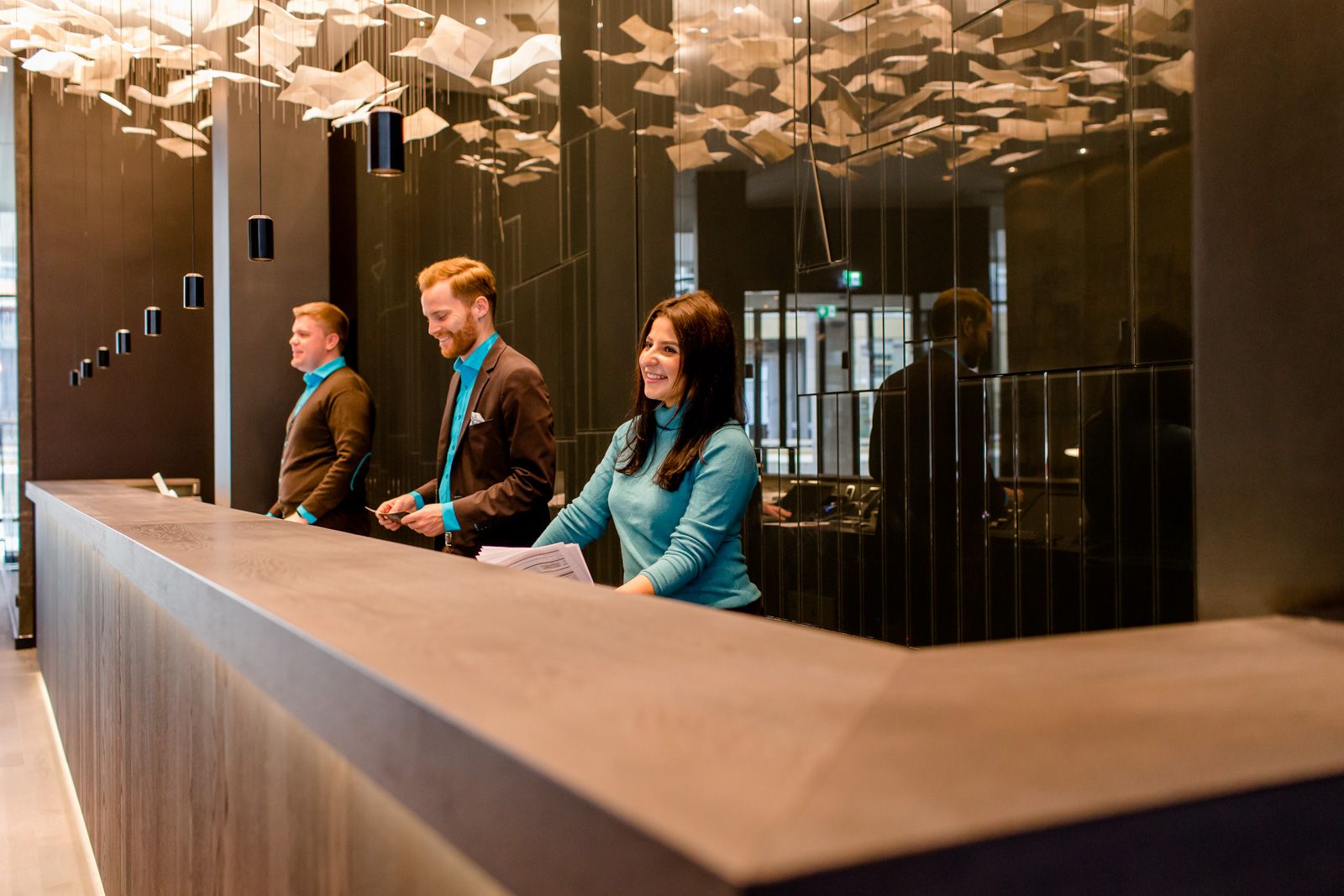 Designhotel Frankfurt Römer Motel One Rezeption mit drei Mitarbeitenden