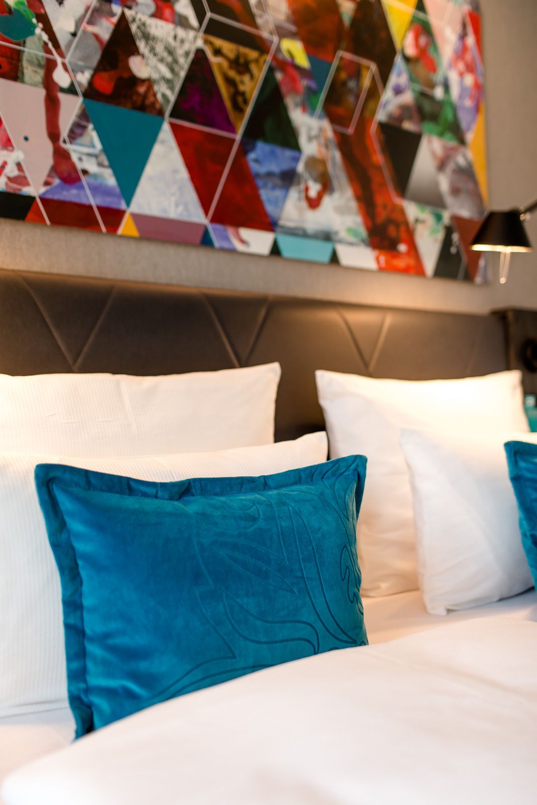 Hotel Frankfurt Römer Motel One Nahaufnahme auf Zierkissen in türkis und weiße Kopfkissen, die auf einem Doppelbett liegen