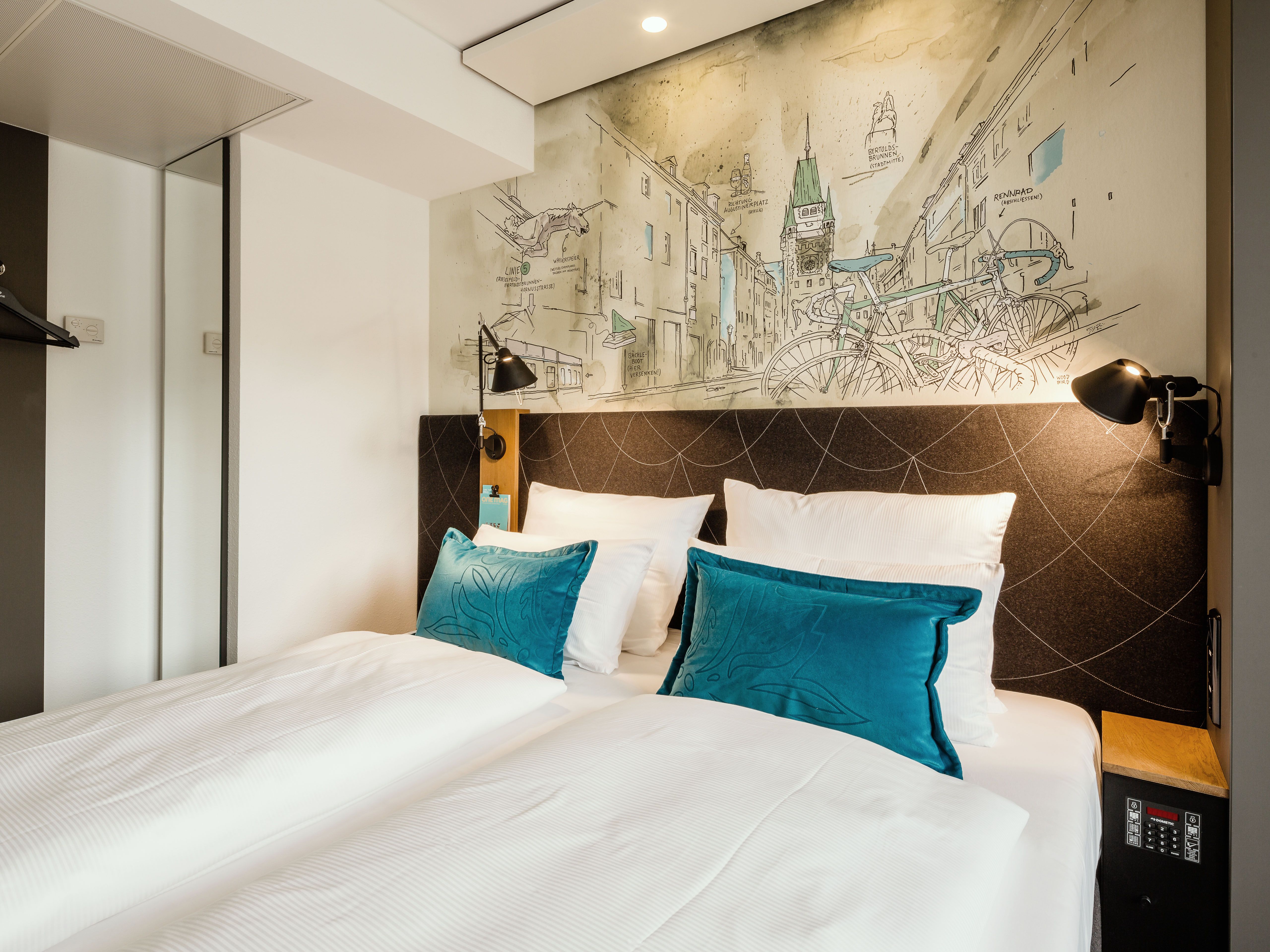 Hotel Freiburg Motel One Zimmer mit Blick auf komfortables Doppelbett und zwei Zierkissen