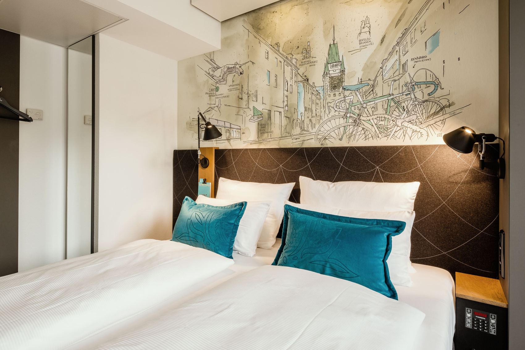 Hotel Freiburg Motel One Zimmer mit Blick auf komfortables Doppelbett und zwei Zierkissen
