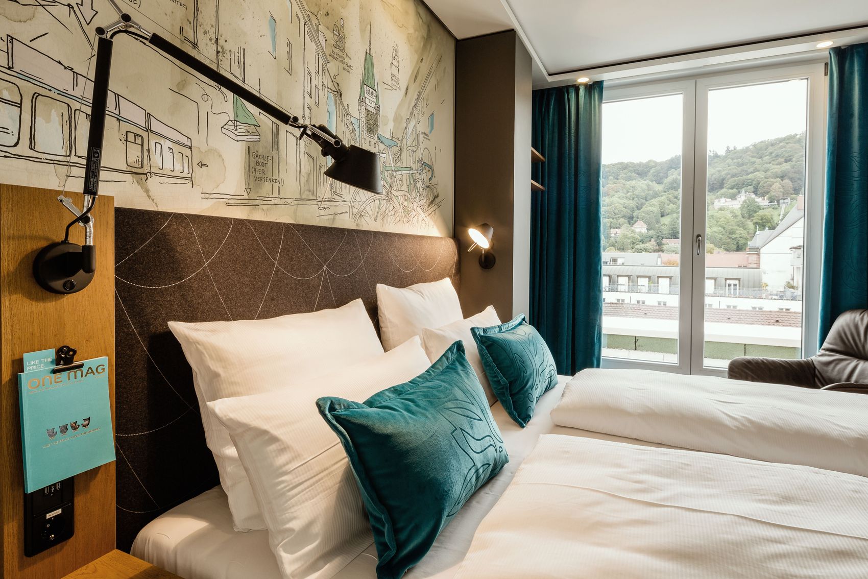 Hotel Freiburg Motel One seitlicher Blick über geräumiges Doppelbett durch ein bodentiefes Fenster