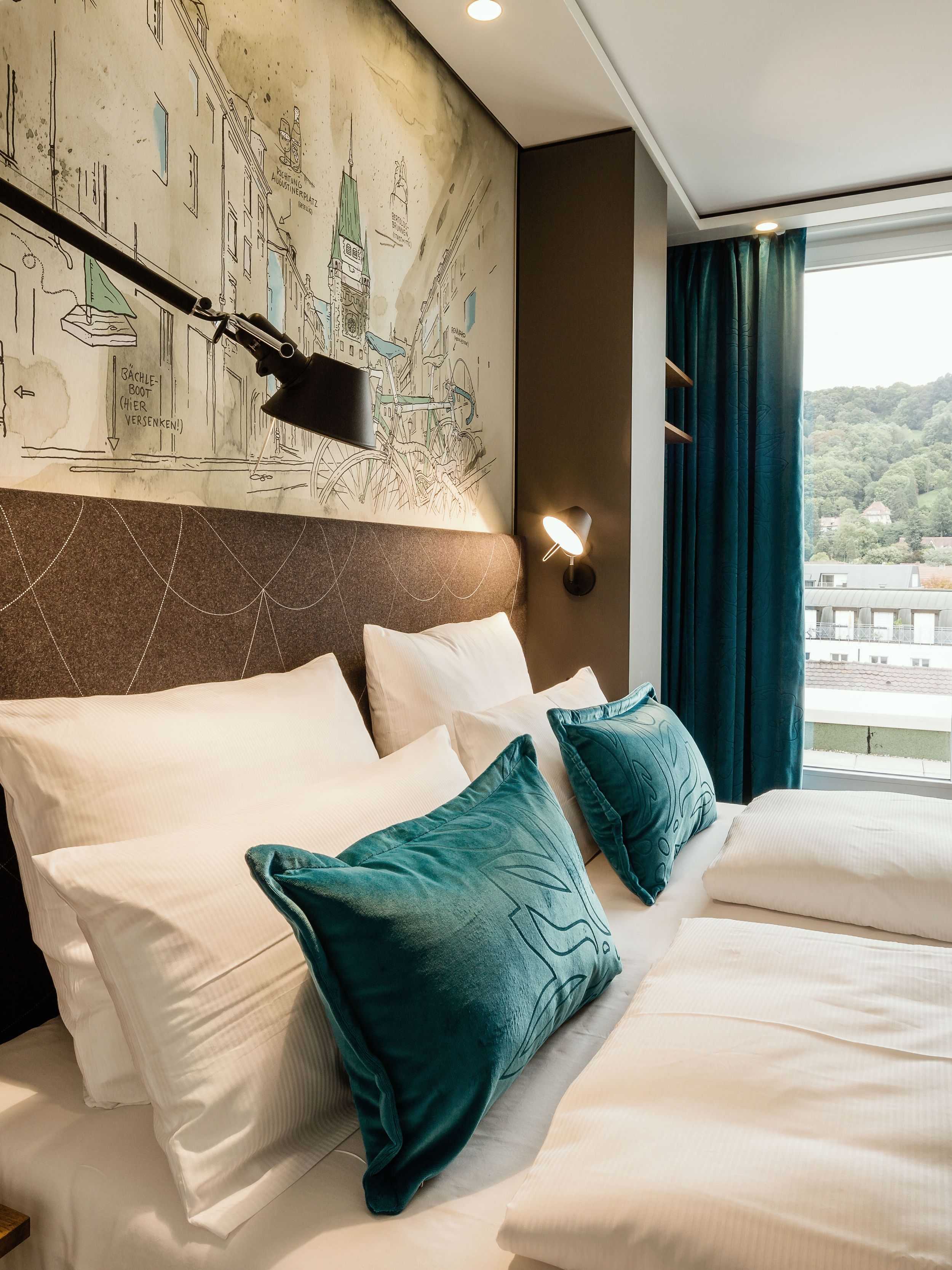 Hotel Freiburg Motel One seitlicher Blick über geräumiges Doppelbett durch ein bodentiefes Fenster
