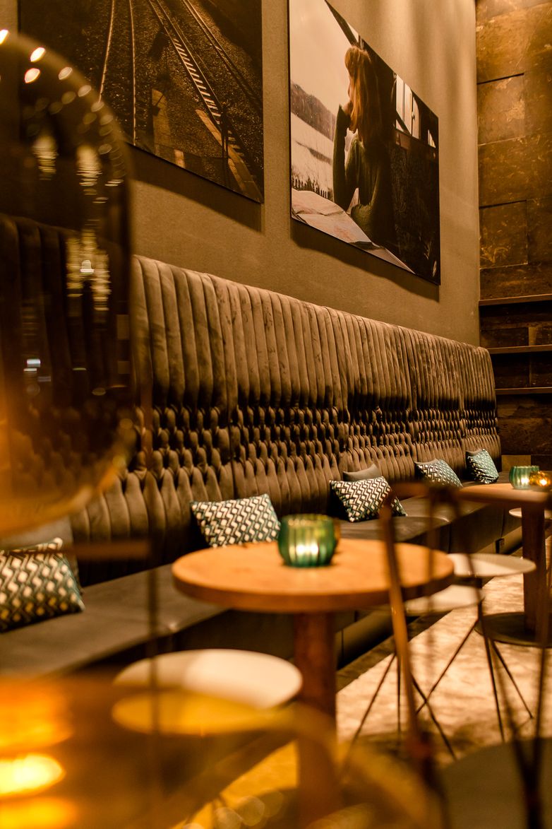 hotel Glasgow Motel One lounge with a view, featuring a long bench with tables in front and chairs for relaxing