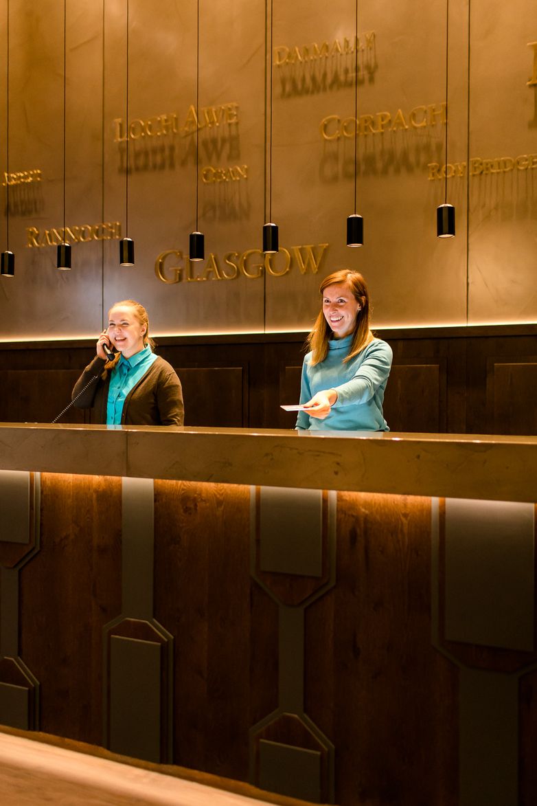 hotel Glasgow Motel One reception desk with two smiling hotel employees