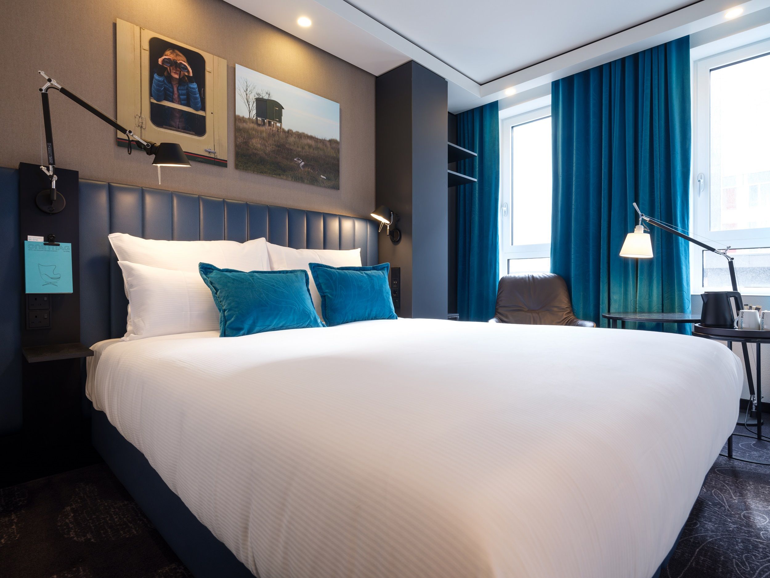 Designhotel Glasgow Motel One helles Zimmer mit großem Doppelbett sowie ein Sessel mit Beistelltisch