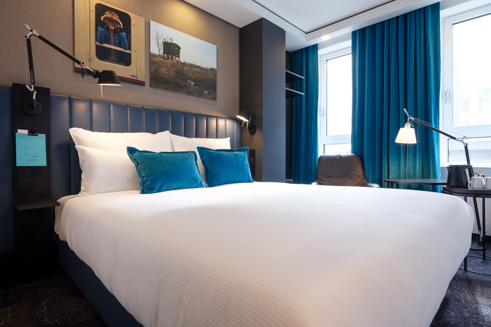 Designhotel Glasgow Motel One helles Zimmer mit großem Doppelbett sowie ein Sessel mit Beistelltisch