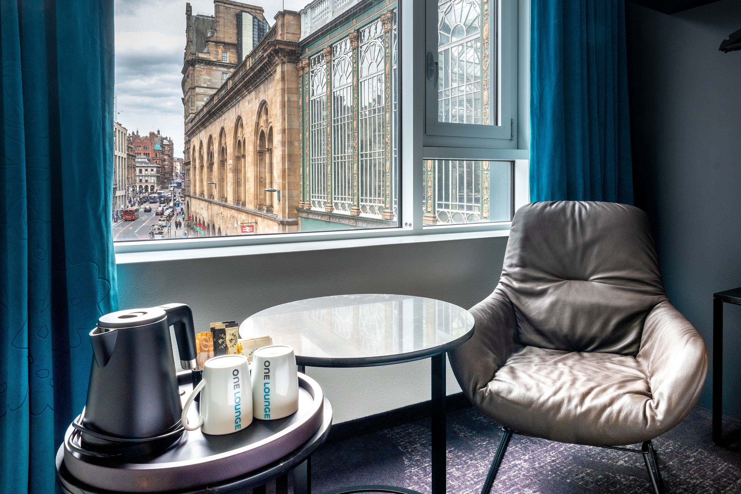 Hotel Glasgow Motel One Zimmer mit Sessel, Beistelltisch, Wasserkocher und zwei Tassen vor großem Fenster