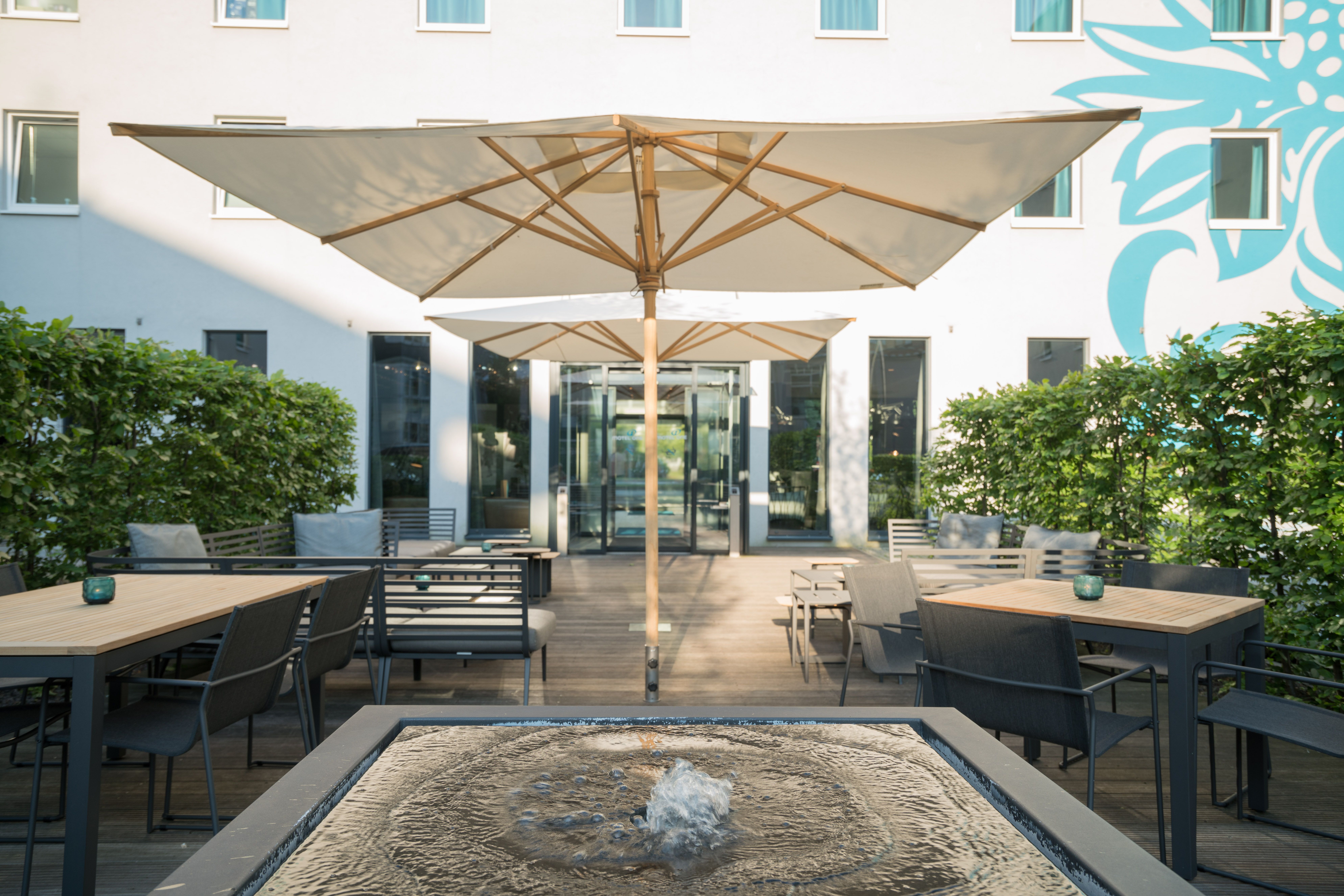 Hotel Hamburg Airport Motel One Terrasse mit Sitzgelegenheiten und Sonnenschirmen