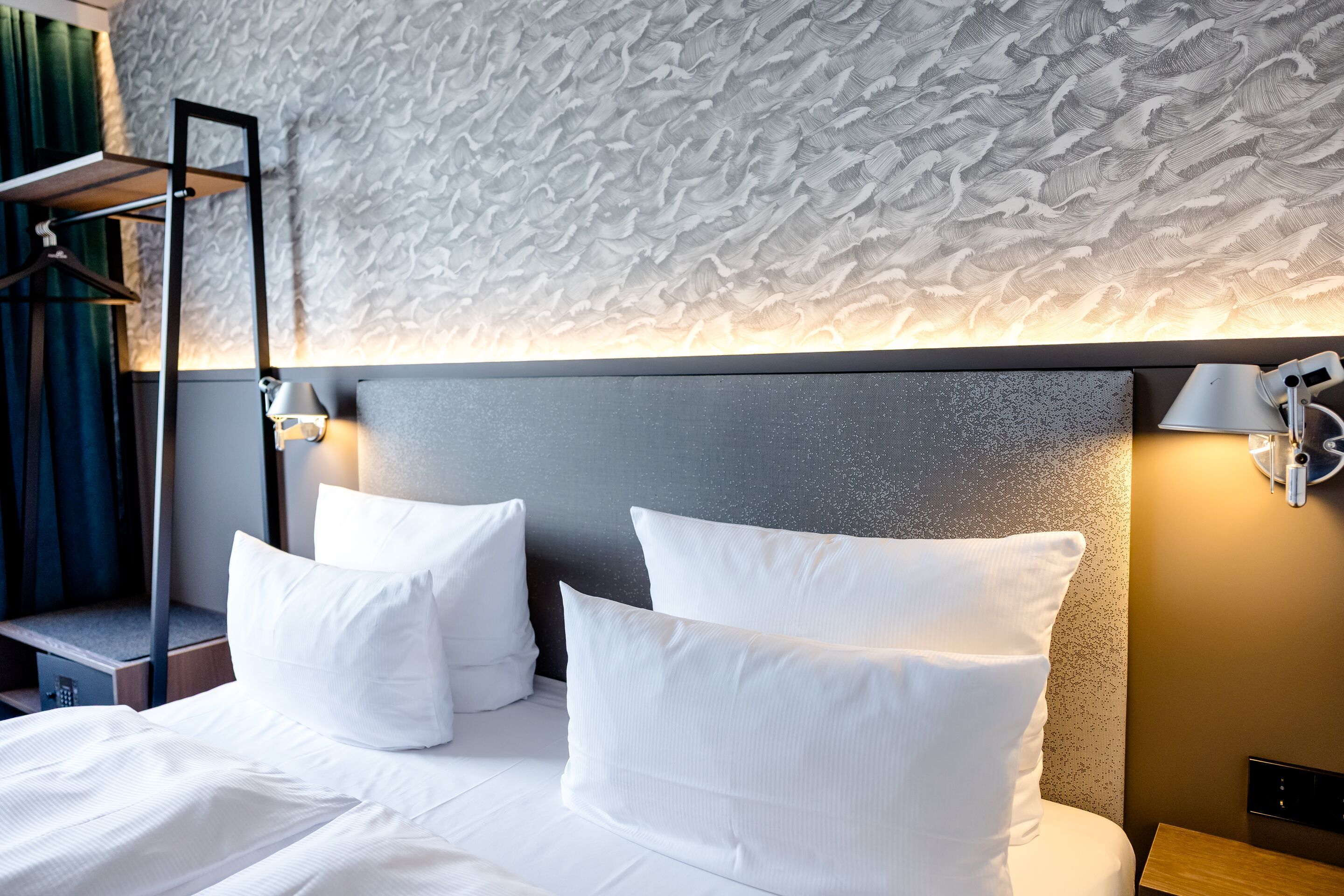 Designhotel Hamburg-Alster Motel One Zimmer mit gemütlichem Doppelbett, weichen weißen Kissen, indirekter Beleuchtung und stilvoller Wandgestaltung für entspannten Schlafkomfort.