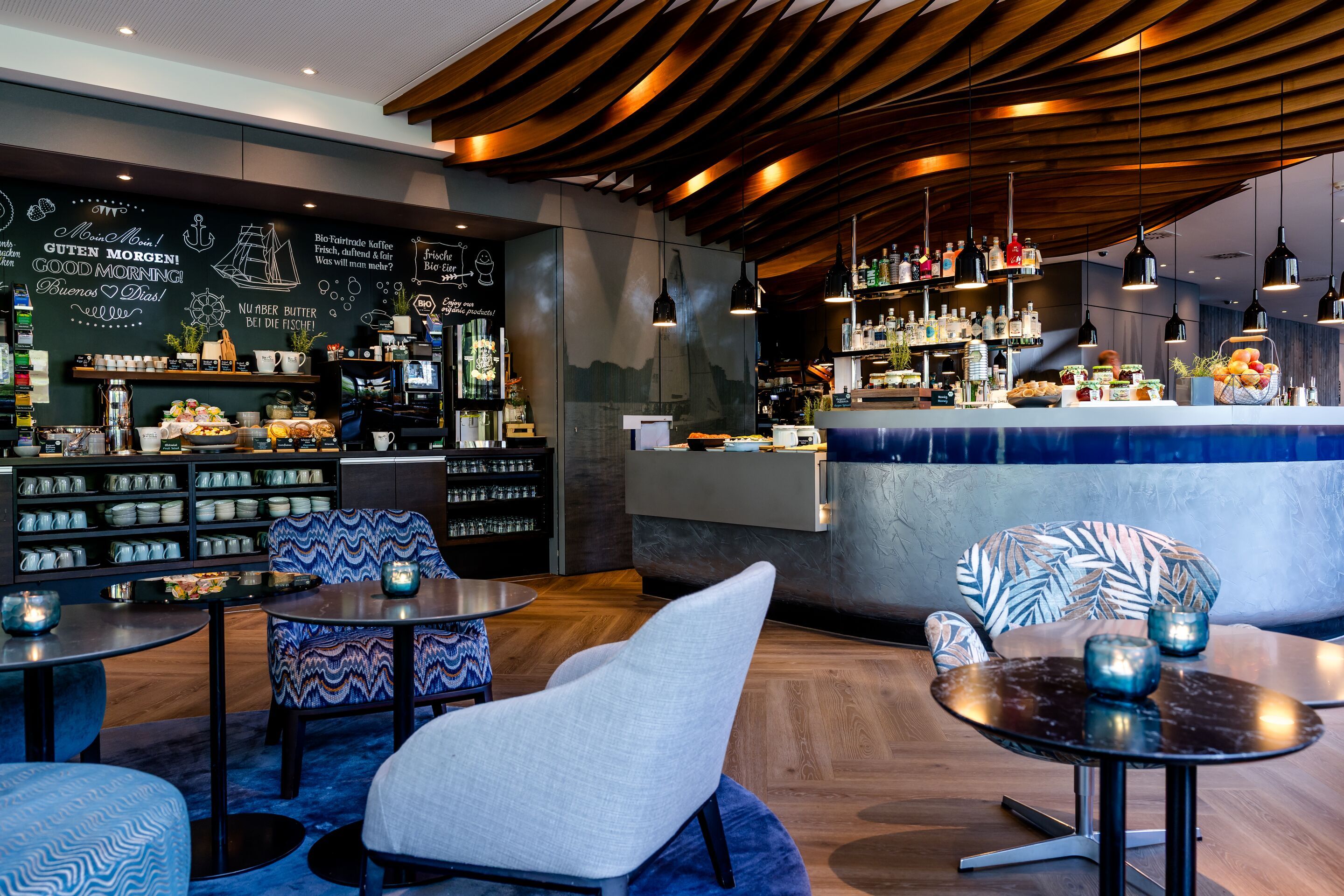 Hotel Hamburg-Alster Motel One Frühstücksbereich mit Sitzgelegenheiten, sowie Blick auf das Buffet im Hintergrund.
