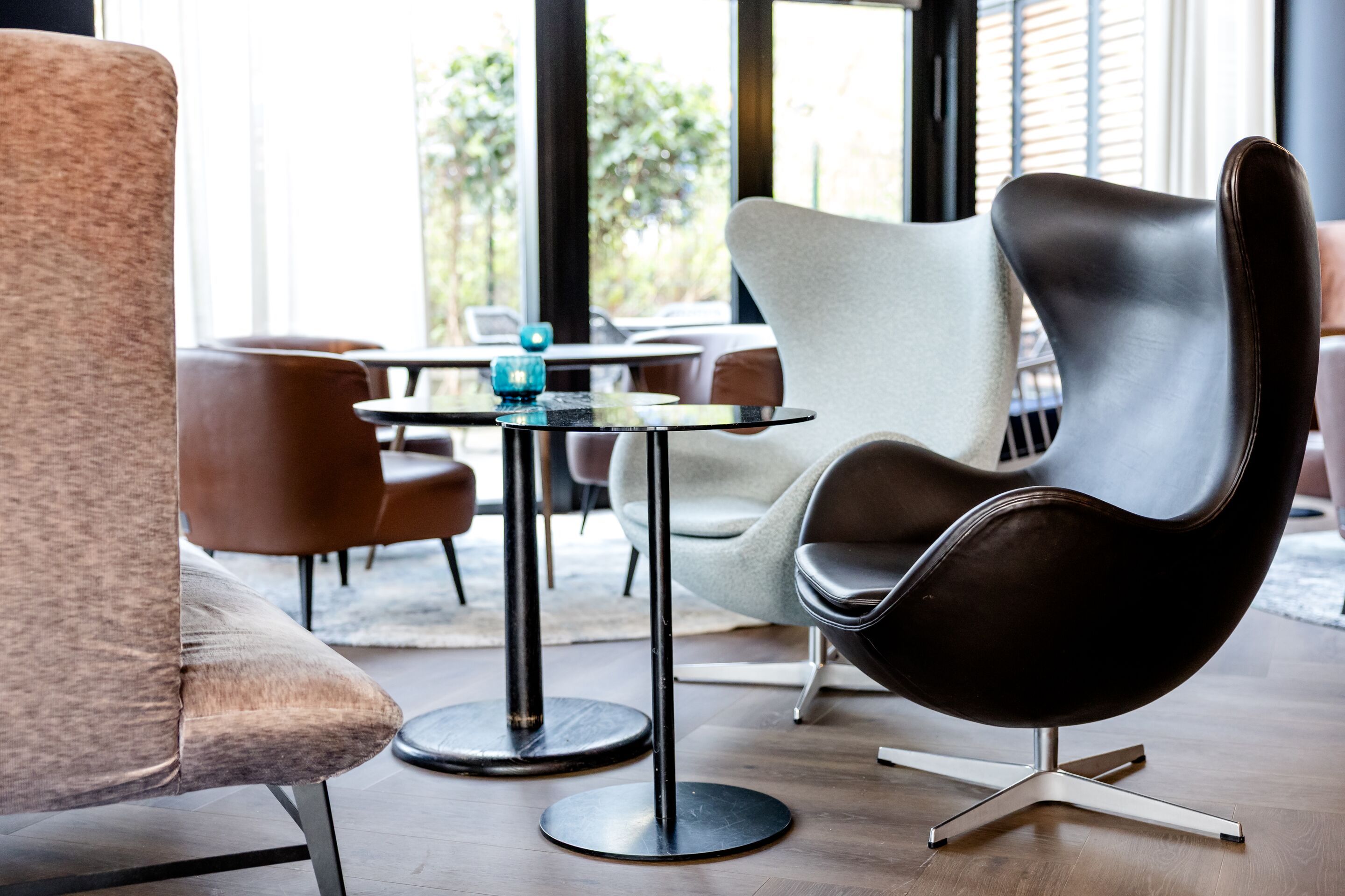 Hotel Hamburg-Alster Motel One helle Lounge mit stilvollen Sesseln und kleinen Tischen, lichtdurchflutet durch große und bodentiefe Fenster.