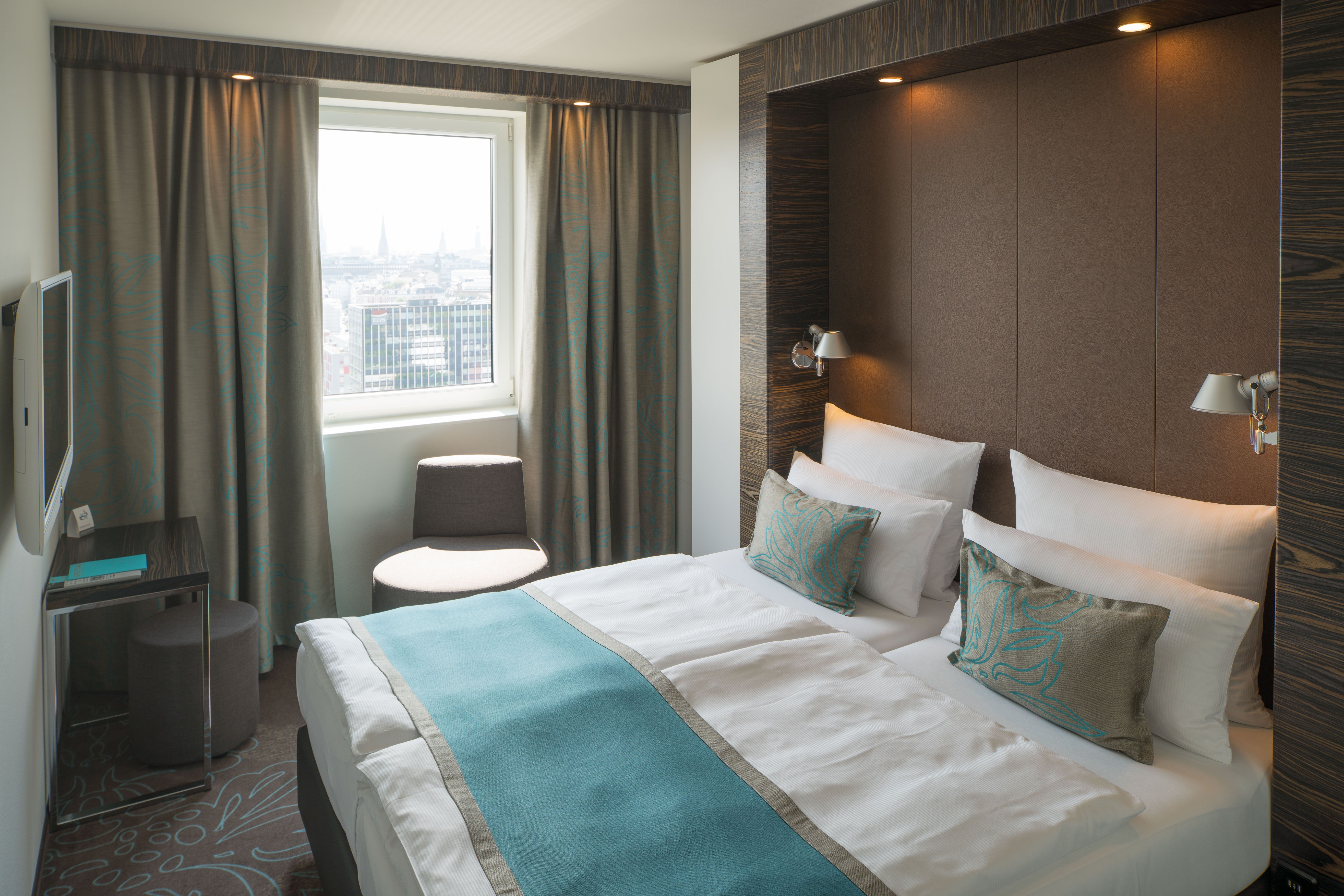 designhotel Hamburg Alster Motel One double room with bed, desk, two armchairs and TV on the wall