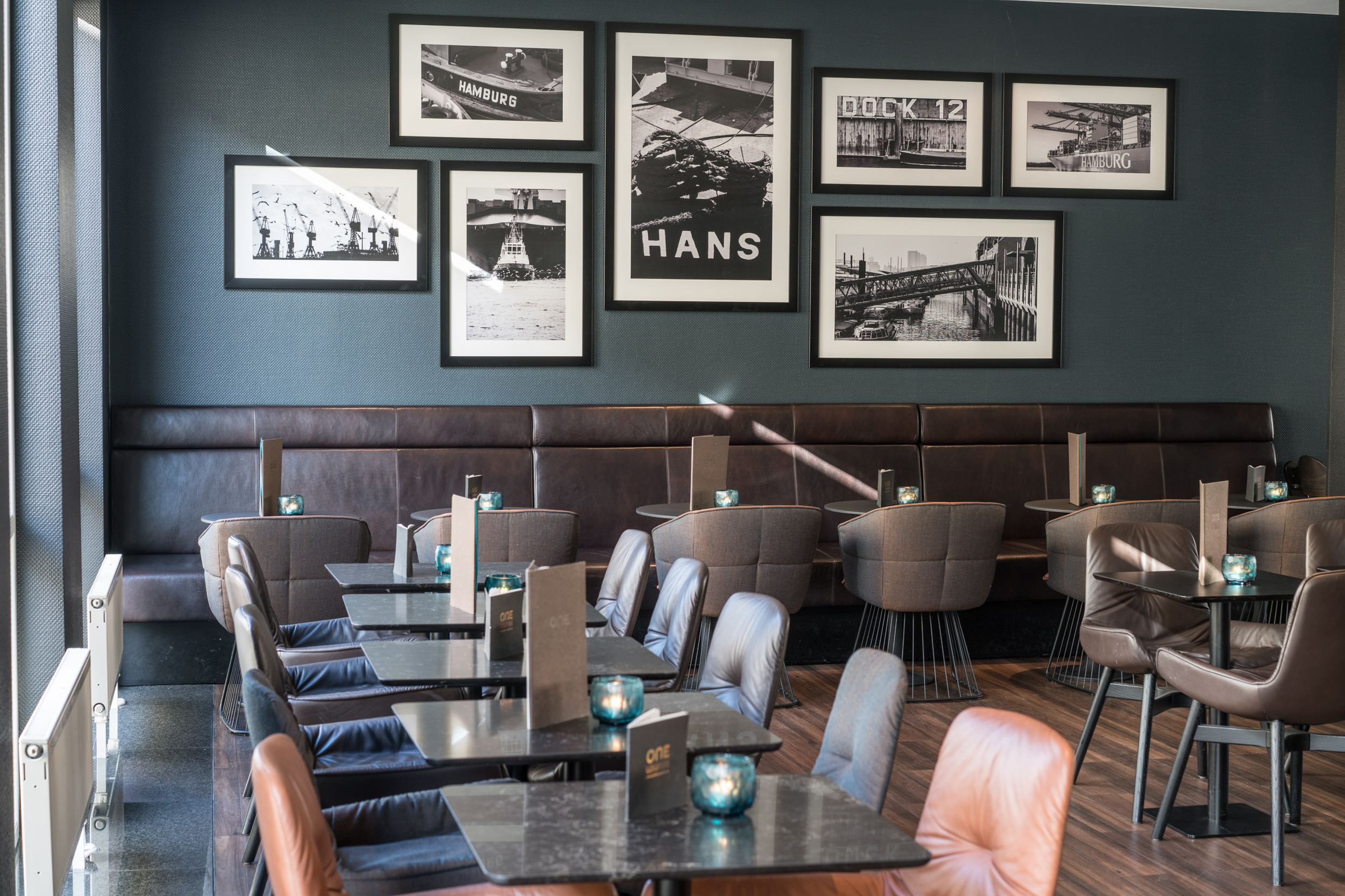 Hotel Hamburg Altona Motel One heller Sitzbereich mit mehreren Tischen und Stühlen