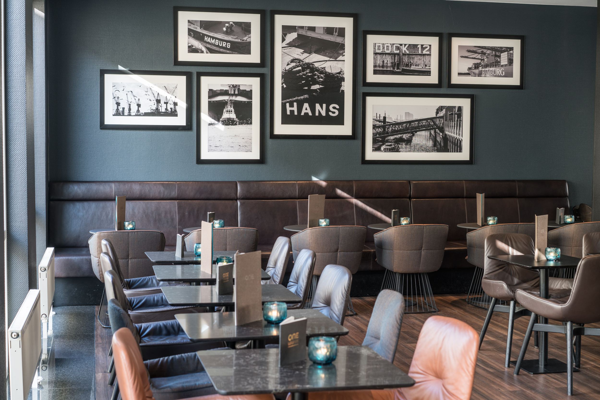 Hotel Hamburg Altona Motel One heller Sitzbereich mit mehreren Tischen und Stühlen