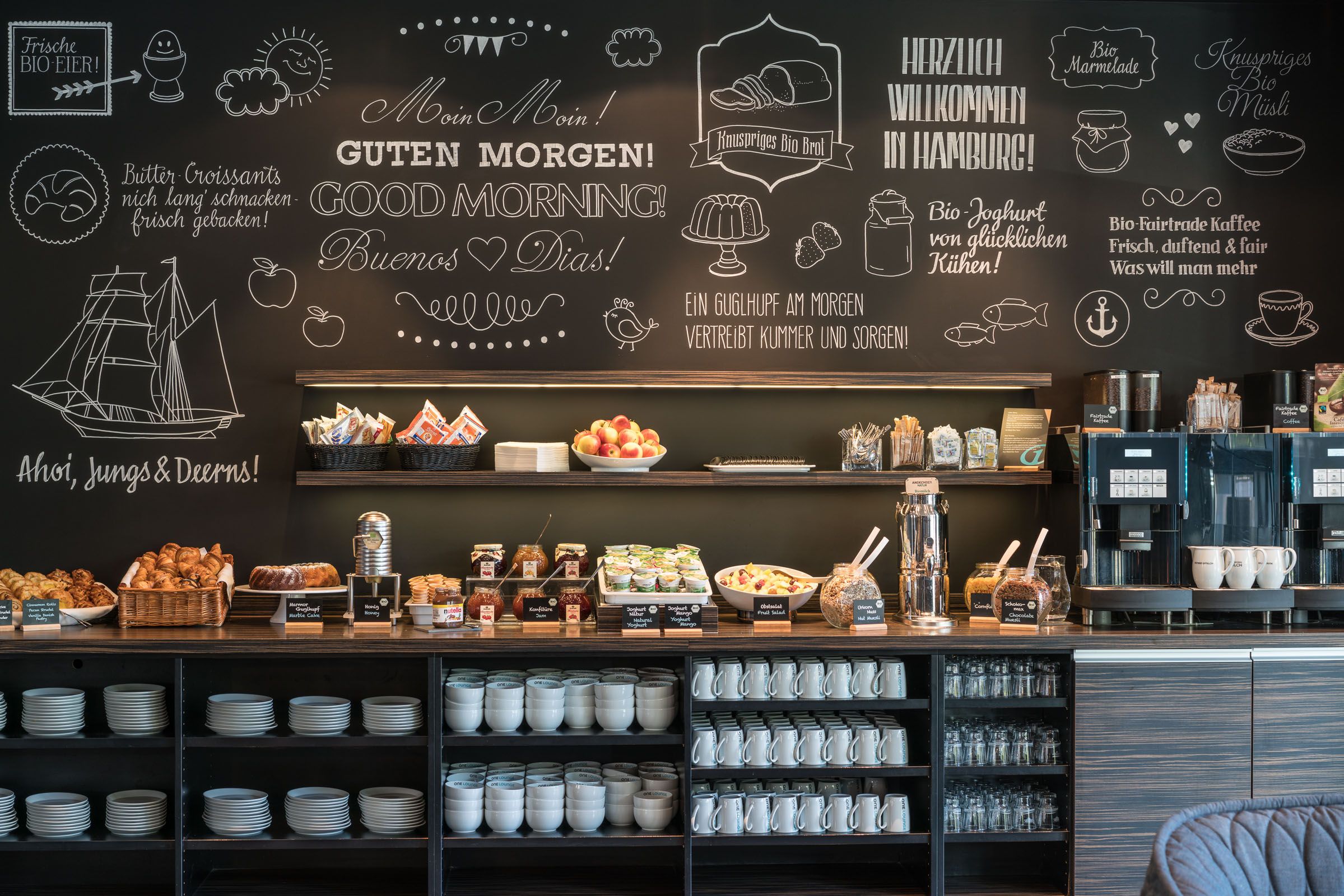 Hotel Hamburg Altona Motel One Frühstücksbuffet mit großer Auswahl an Essen und Getränken sowie Geschirr