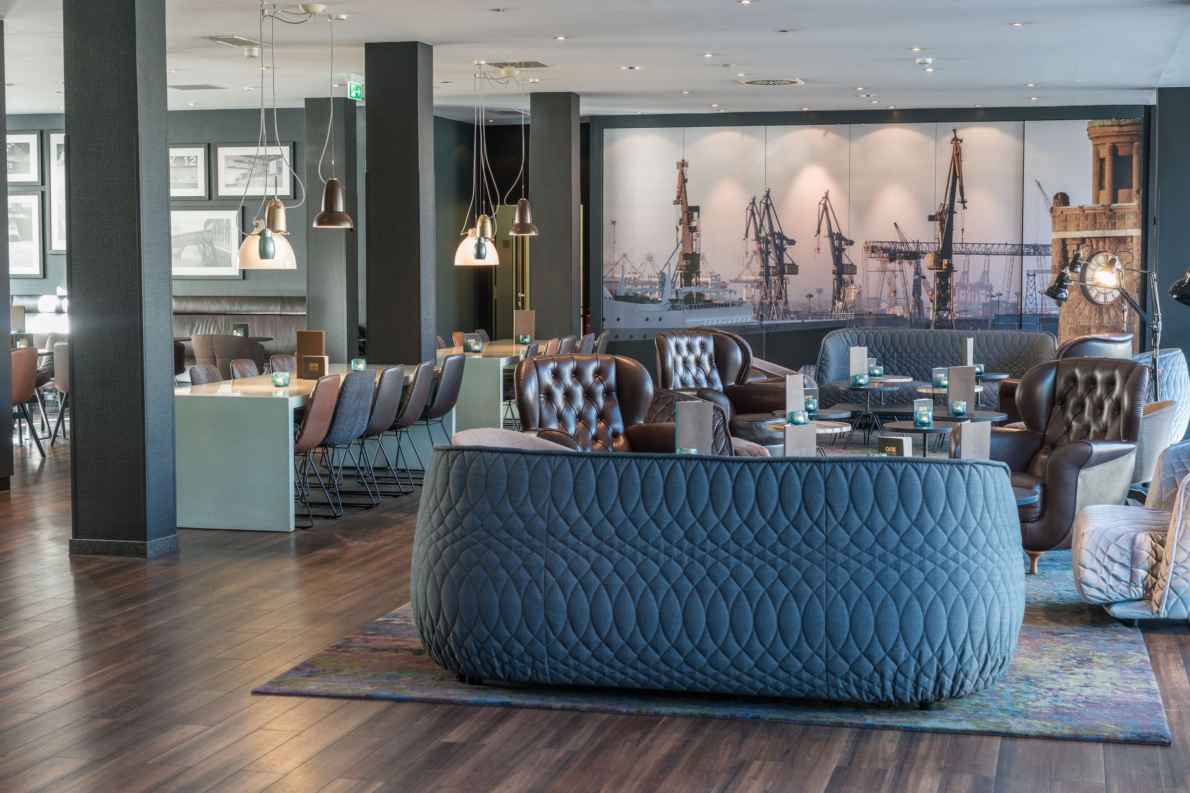 Designhotel Hamburg Altona Motel One lichtdurchflutete Lounge mit mehreren Tischen, Stühlen, Sesseln und Sofas
