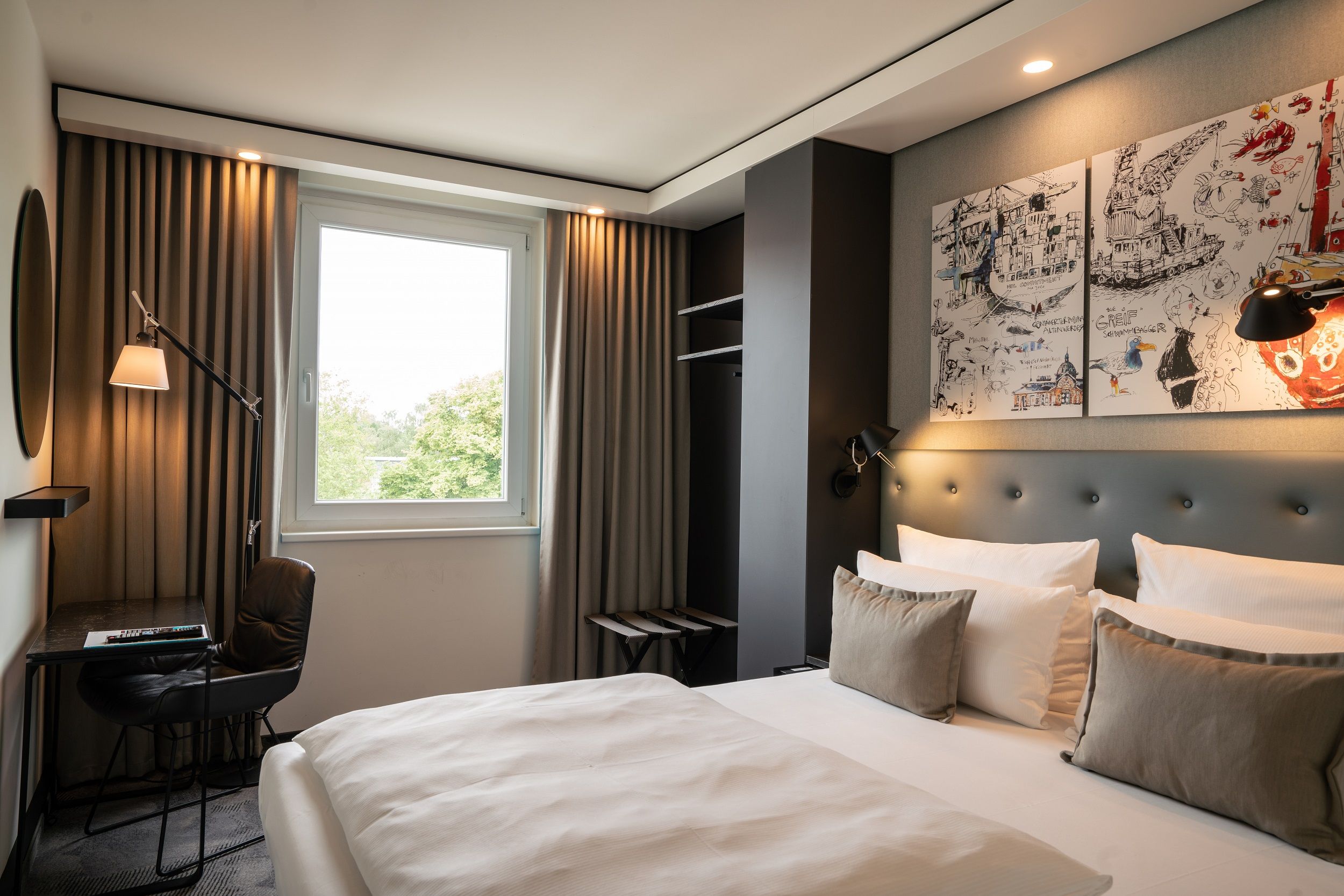 Hotel Hamburg Altona Motel One helles Zimmer mit Doppelbett, Schreibtisch, Stuhl und rundem Spiegel