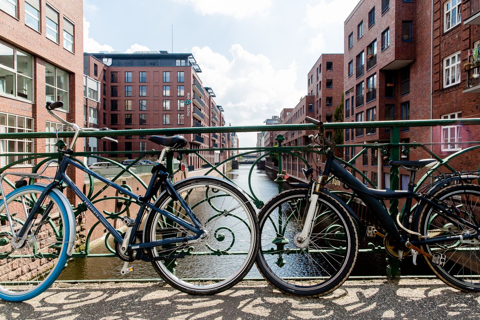 Hotel Hamburg Fleetinsel Motel One zwei Fahrräder stehen an einer Brücke über einem Fluss, im Hintergrund das Hotel