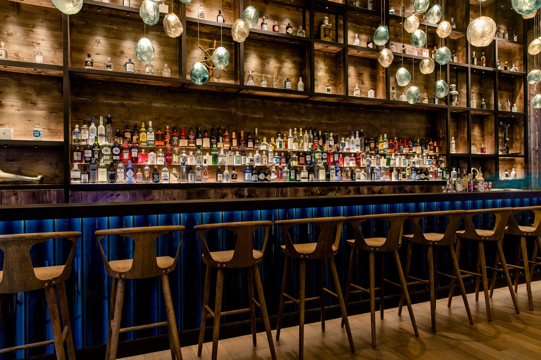 Designhotel Hamburg Fleetinsel Motel One Blick auf die lange Bar mit Spirituosen in den Regalen sowie Barhockern am Tresen