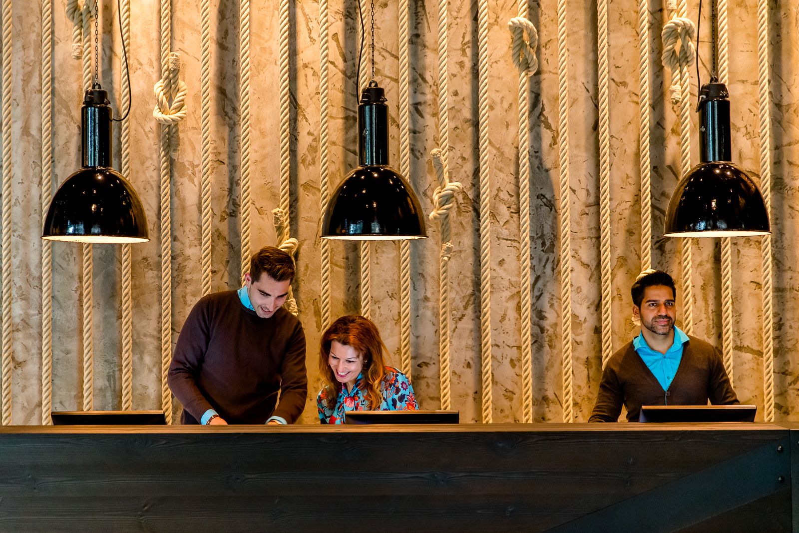 Hotel Hamburg Fleetinsel Motel One Rezeption mit drei Mitarbeitenden