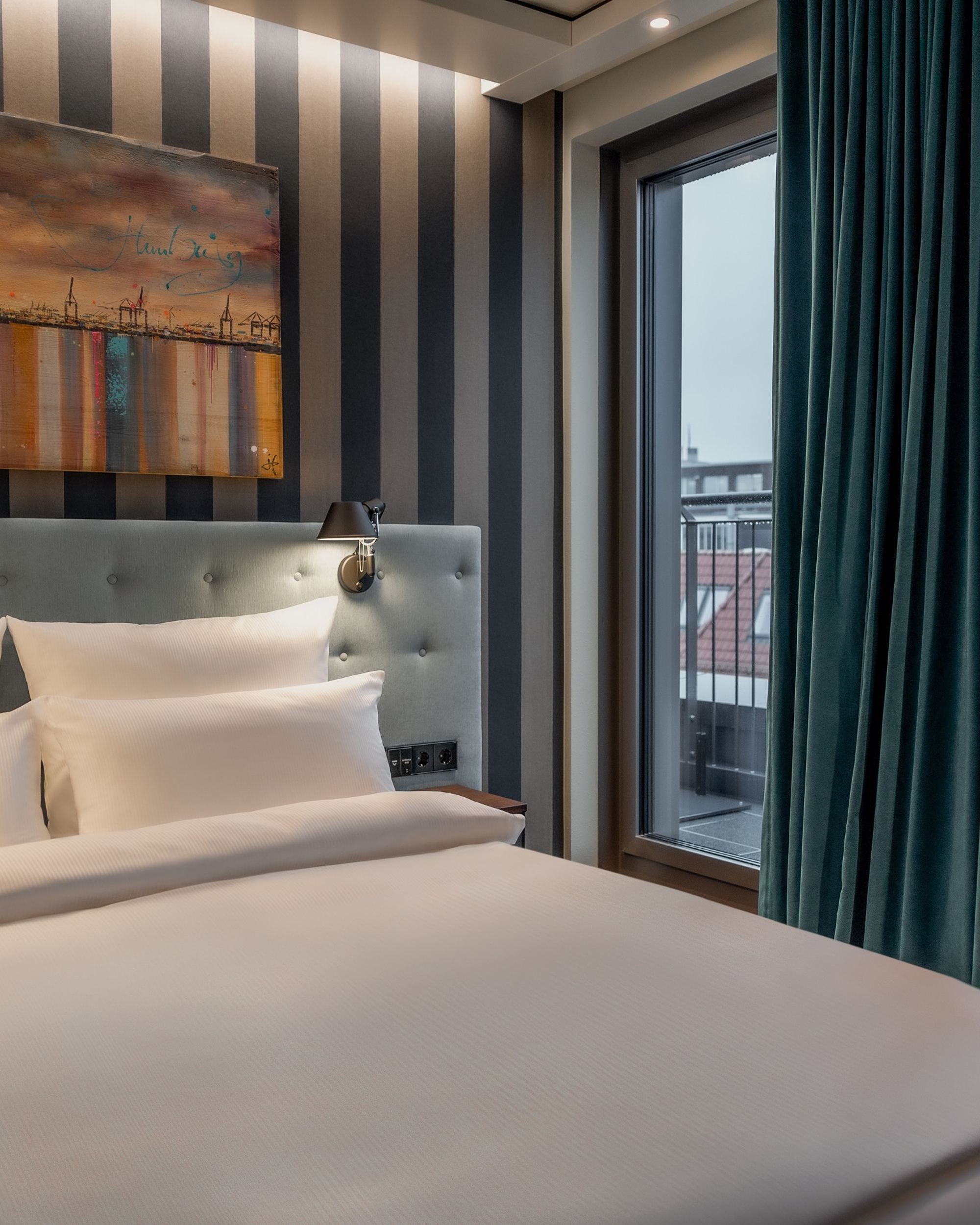 Hotel Hamburg Kontorhaus The Cloud One Zimmer mit großem Doppelbett, Gemälde über dem Bett sowie Balkonzugang