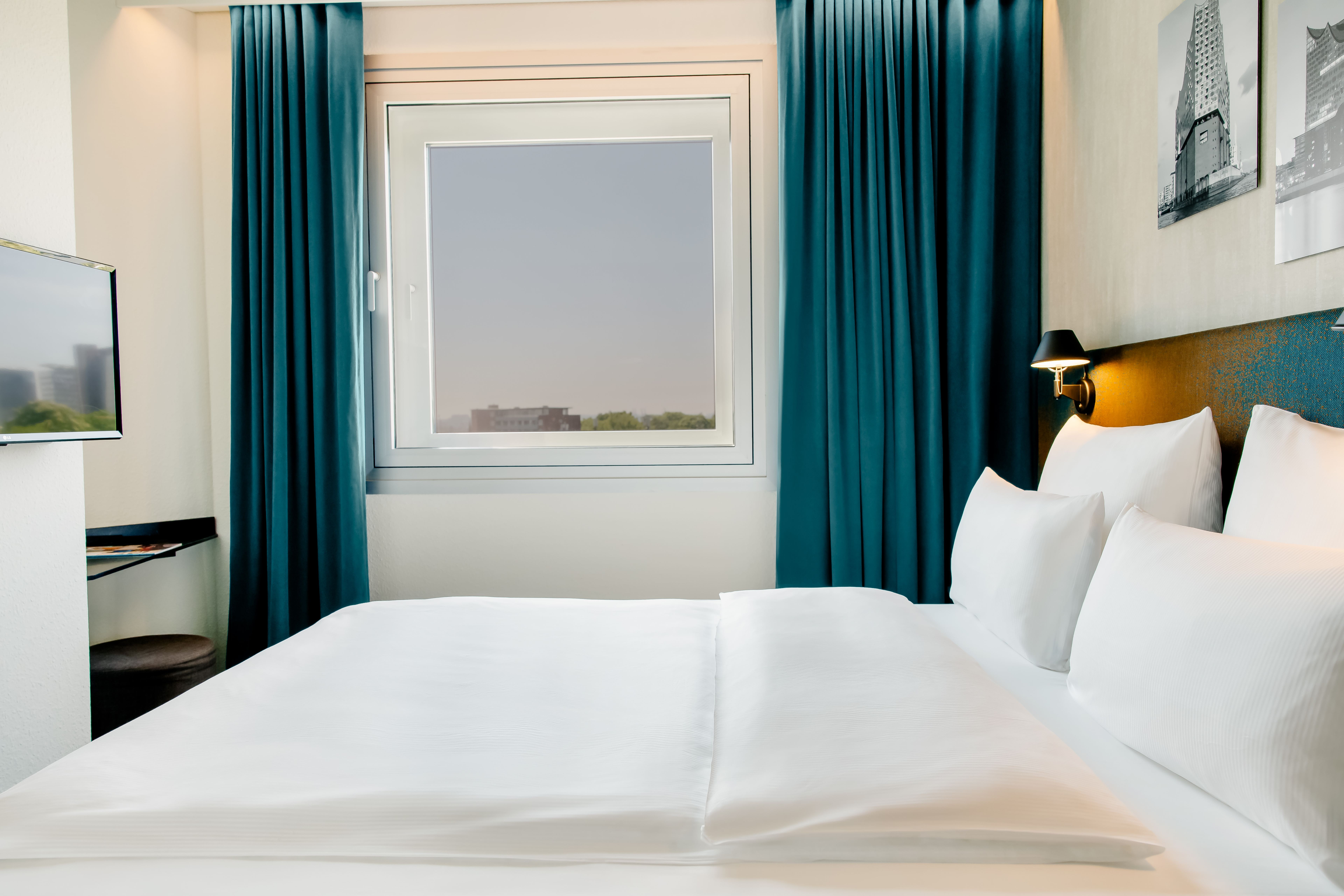 Helles, modernes Hotelzimmer mit großem, bequemem Doppelbett, weißen Bettwäsche, Fenster mit Blick nach draußen und dunkelblauen Vorhängen, das eine gemütliche und ruhige Atmosphäre für erholsamen Aufenthalt schafft. Helles, modernes Hotelzimmer mit großem, bequemem Doppelbett, weißen Bettwäsche, Fenster mit Blick nach draußen und dunkelblauen Vorhängen, das eine gemütliche und ruhige Atmosphäre für erholsamen Aufenthalt schafft.