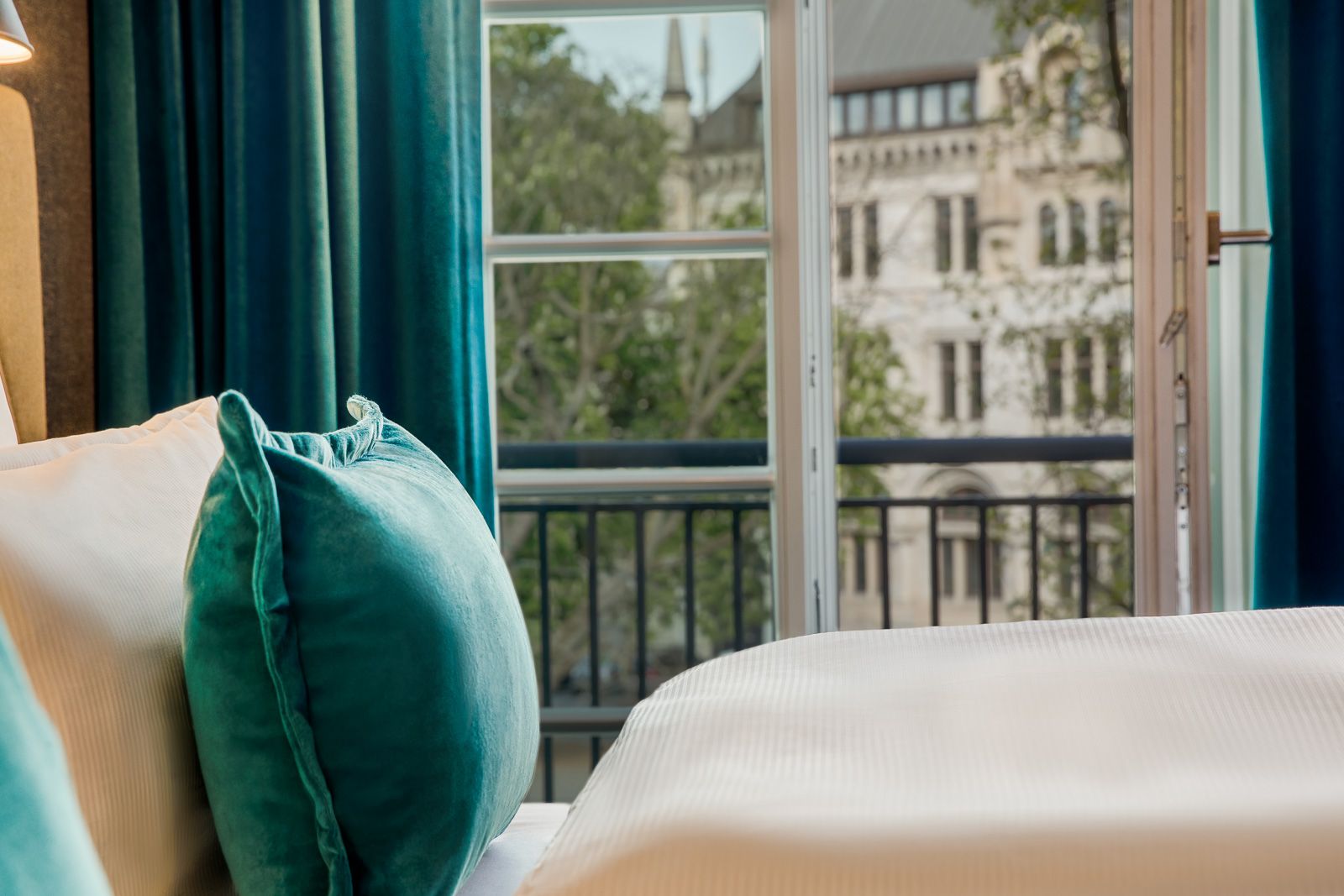 Designhotel Hannover Oper Motel One Nahaufnahme Bett mit Zierkissen und offenem Fenster im Hintergrund