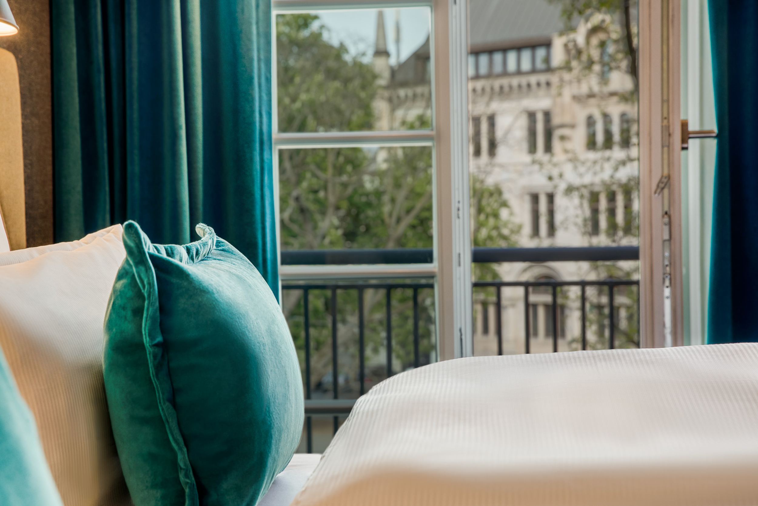 Designhotel Hannover Oper Motel One Nahaufnahme Bett mit Zierkissen und offenem Fenster im Hintergrund