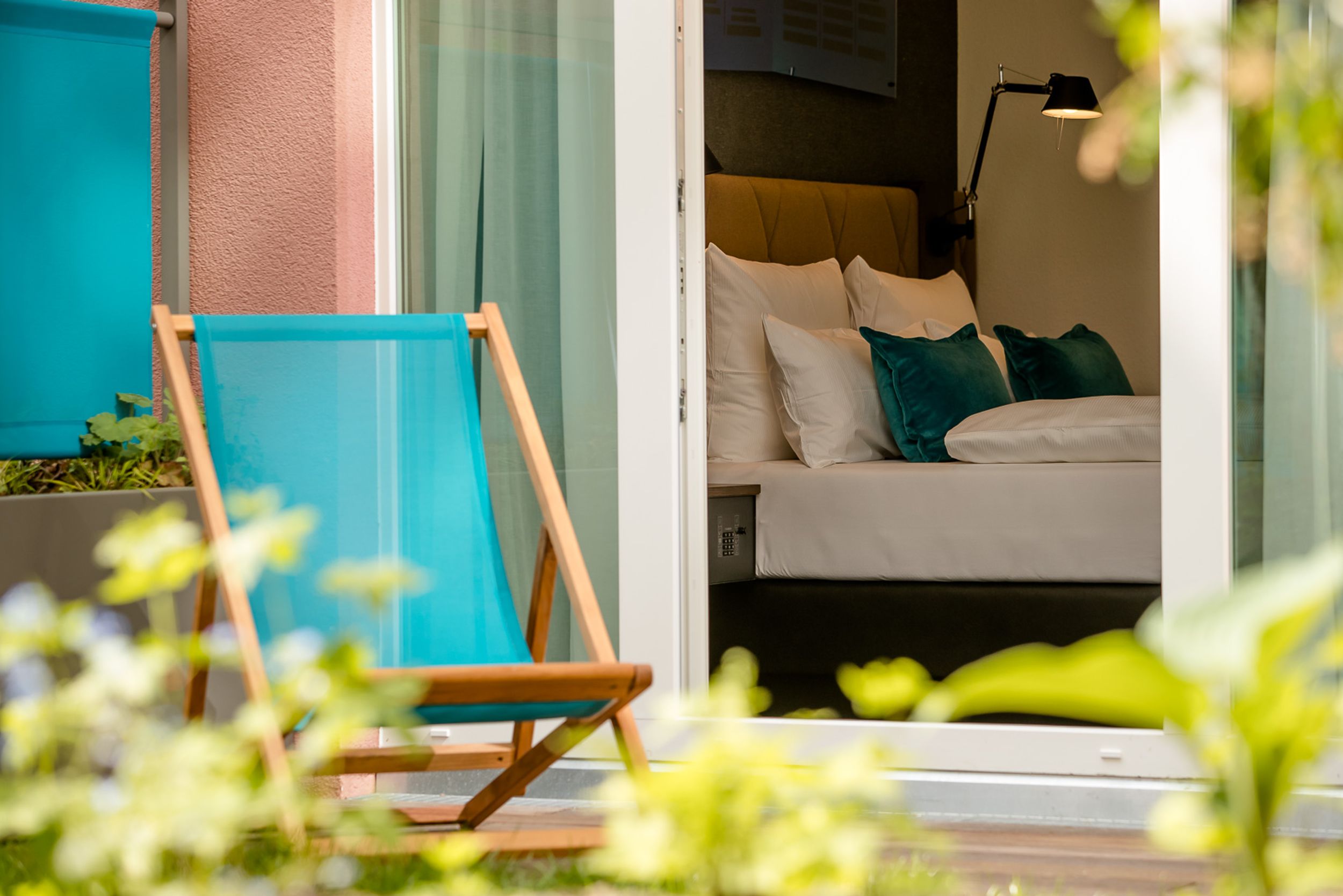 Hotel Hannover Oper Motel One Blick von außen auf einen Liegestuhl vor einem Zimmer mit großem Bett