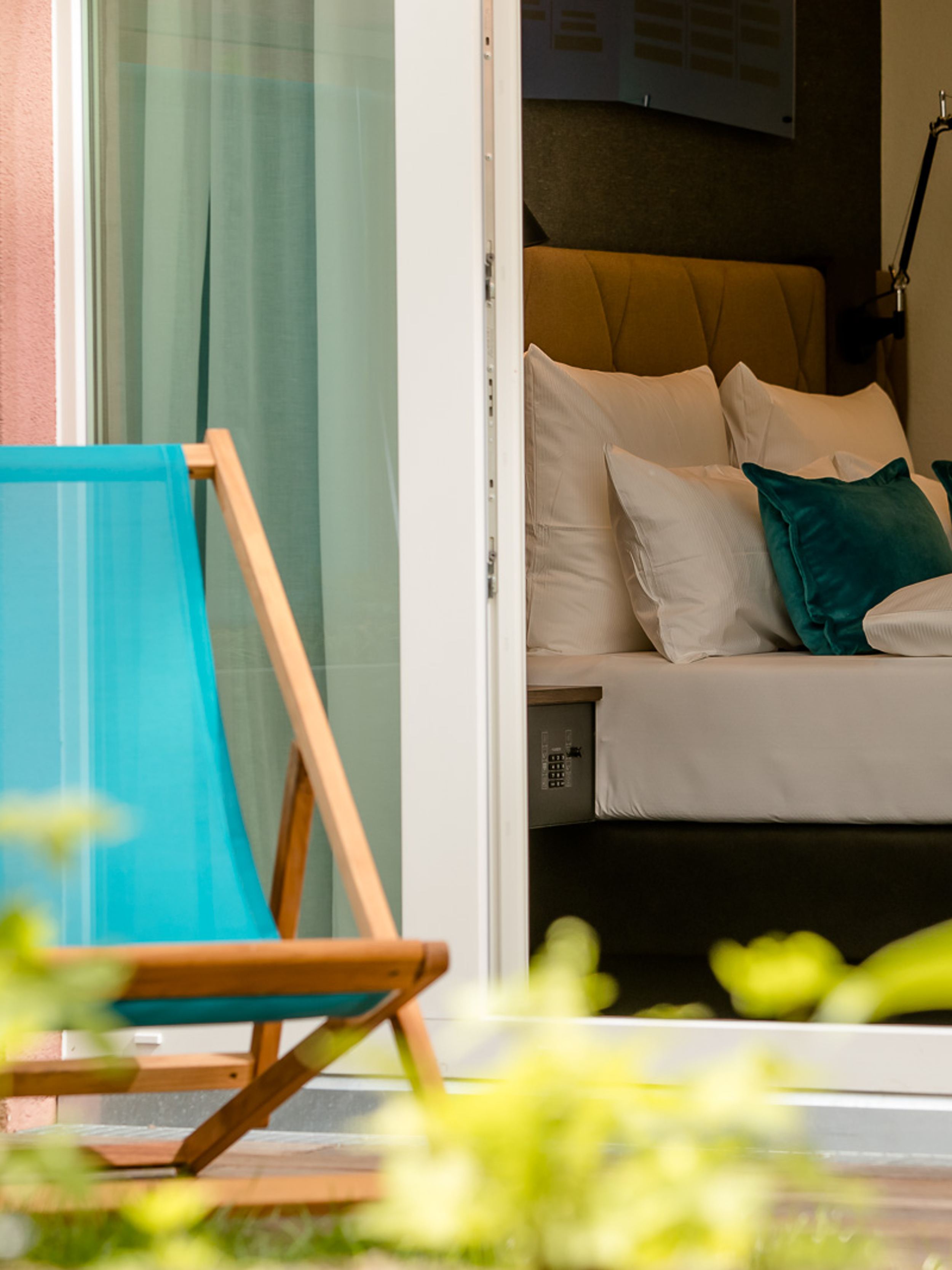 Hotel Hannover Oper Motel One Blick von außen auf einen Liegestuhl vor einem Zimmer mit großem Bett