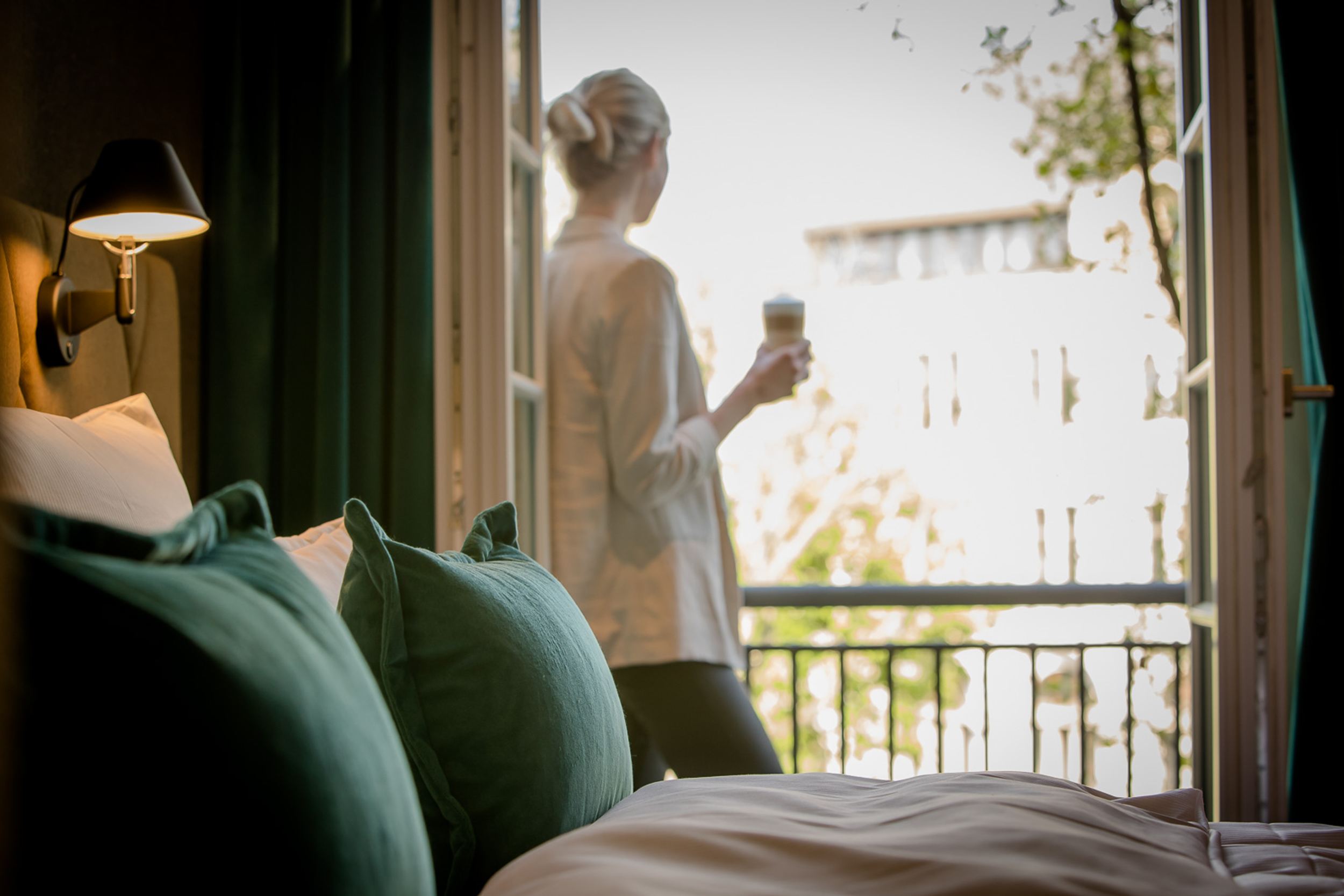 Designhotel Hannover Oper Motel One Zimmer mit Frau an offenem Fenster und Bett im Vordergrund