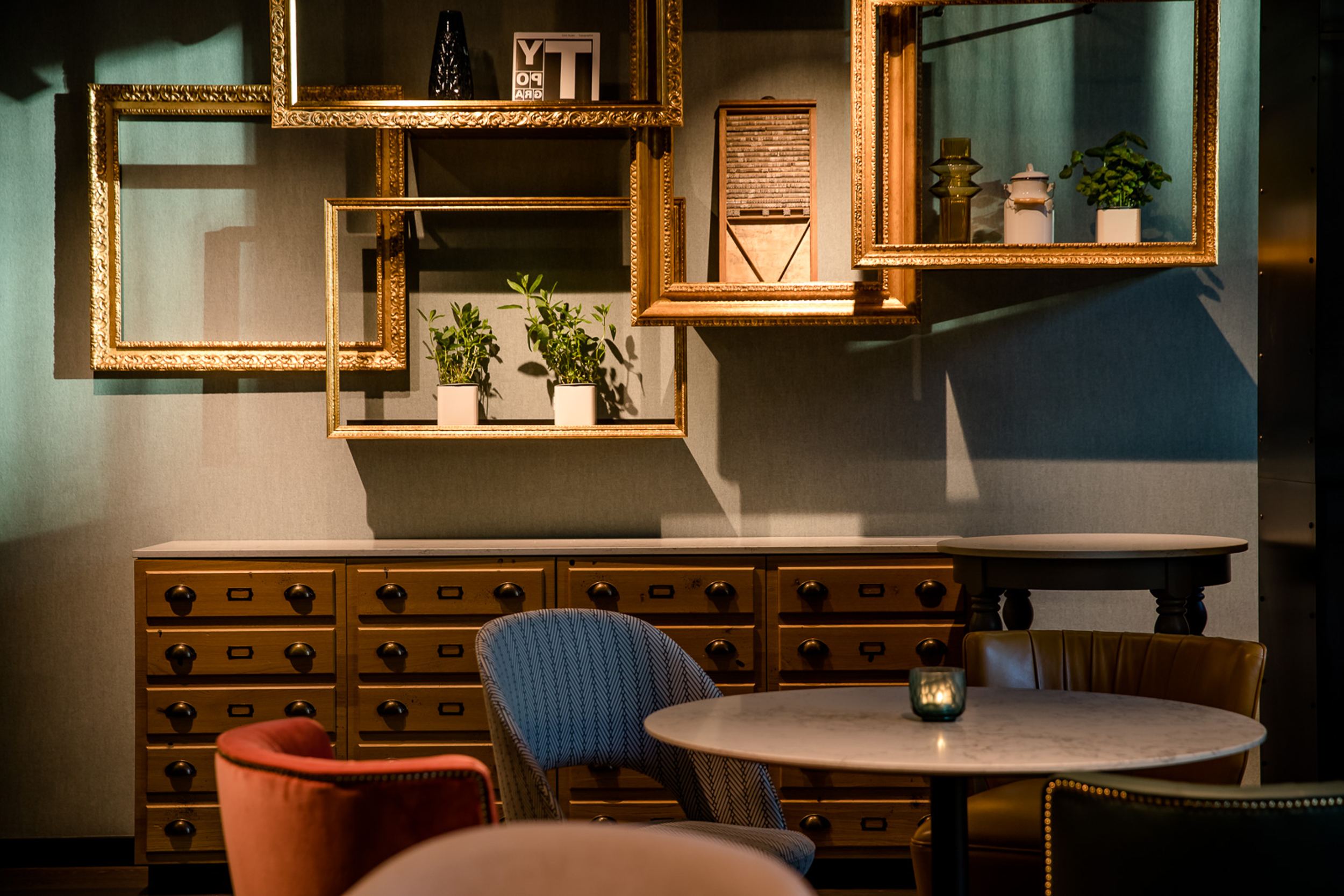 Designhotel Hannover Oper Motel One Tisch mit Stühlen sowie Bilderrahmen an der Wand