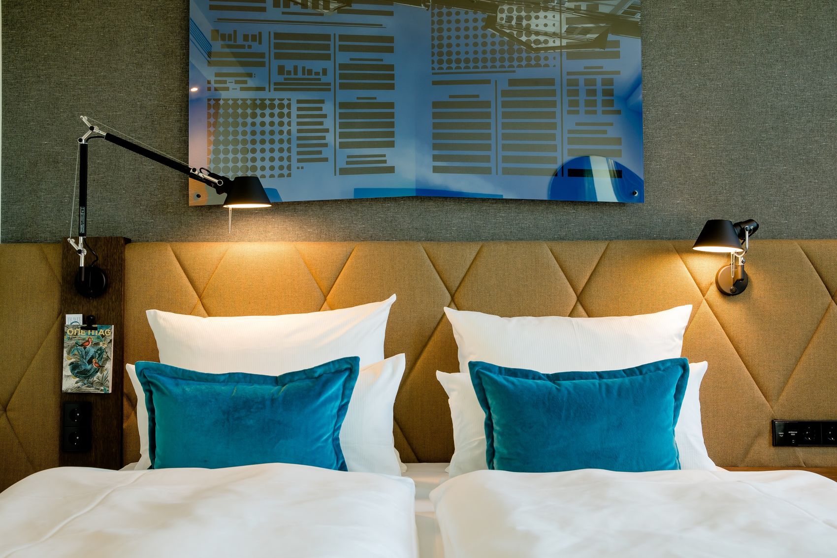 Designhotel Hannover Oper Motel One Blick auf Kopfteil eines Doppelbettes mit zwei Zierkissen in türkis