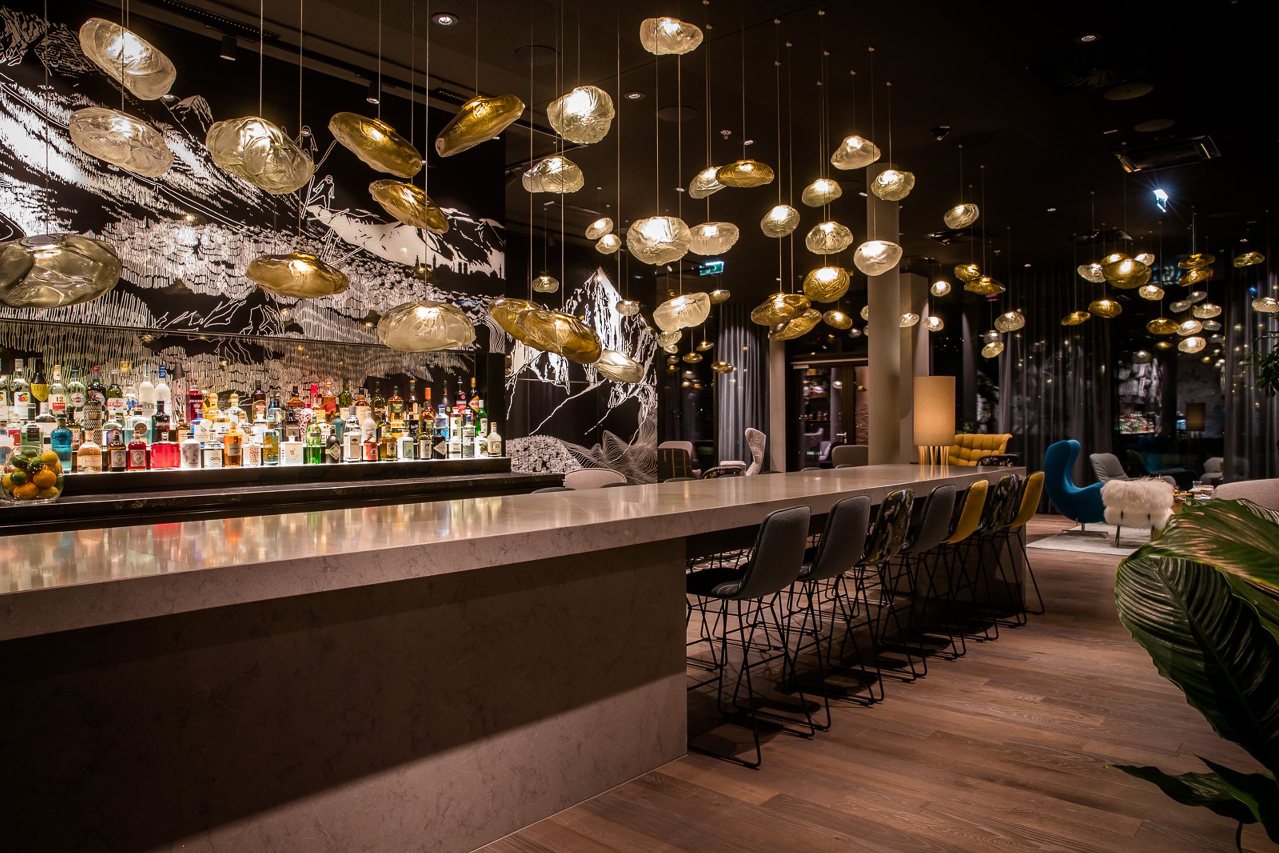 Designhotel Innsbruck Motel One lange Bar bei Abend mit mehreren Barhockern an hohem Tisch