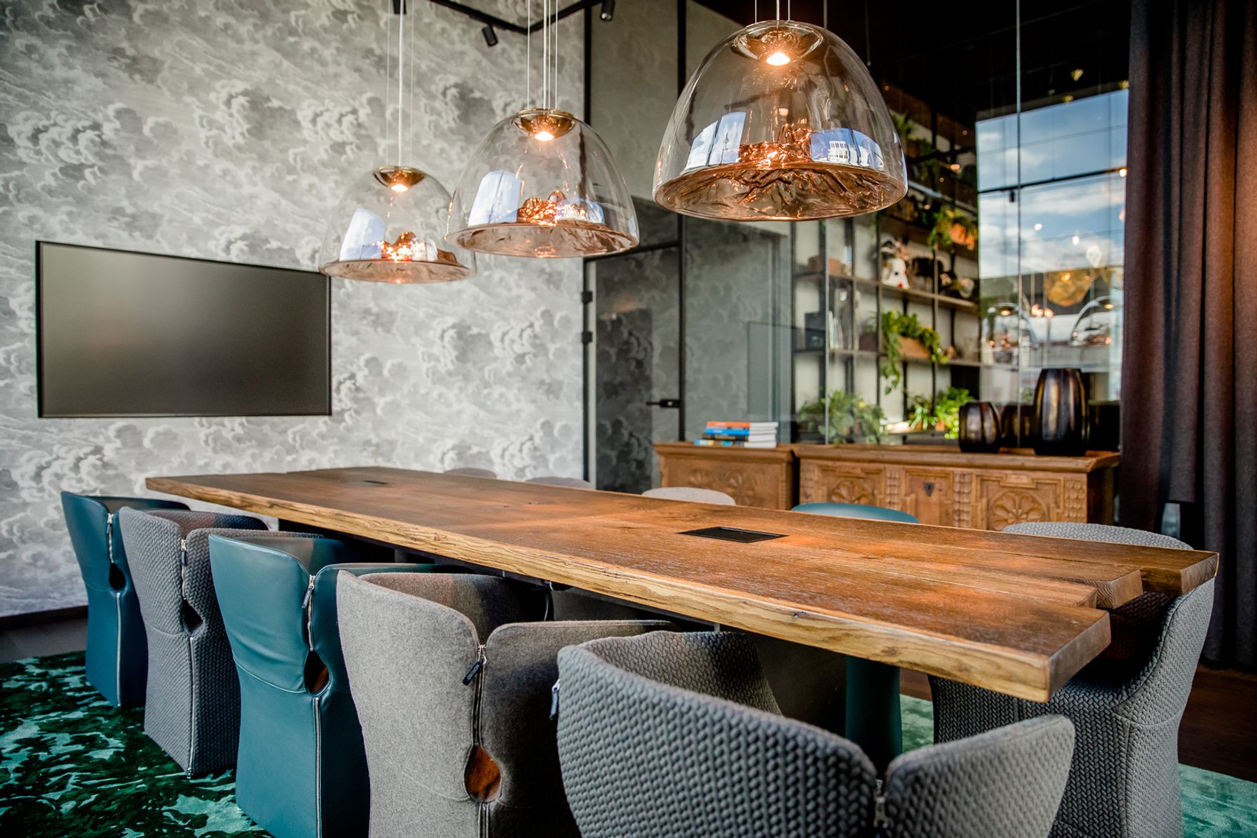 Hotel Innsbruck Motel One heller Meetingraum mit langem Tisch, elf Stühlen und Fernseher an der Wand