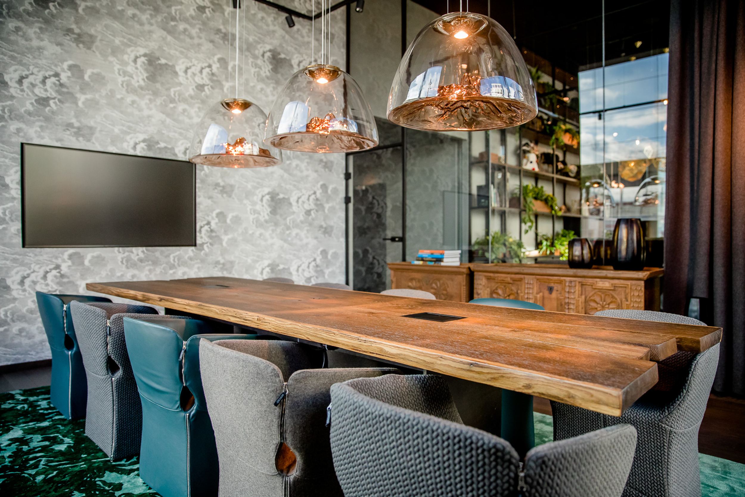 Hotel Innsbruck Motel One heller Meetingraum mit langem Tisch, elf Stühlen und Fernseher an der Wand