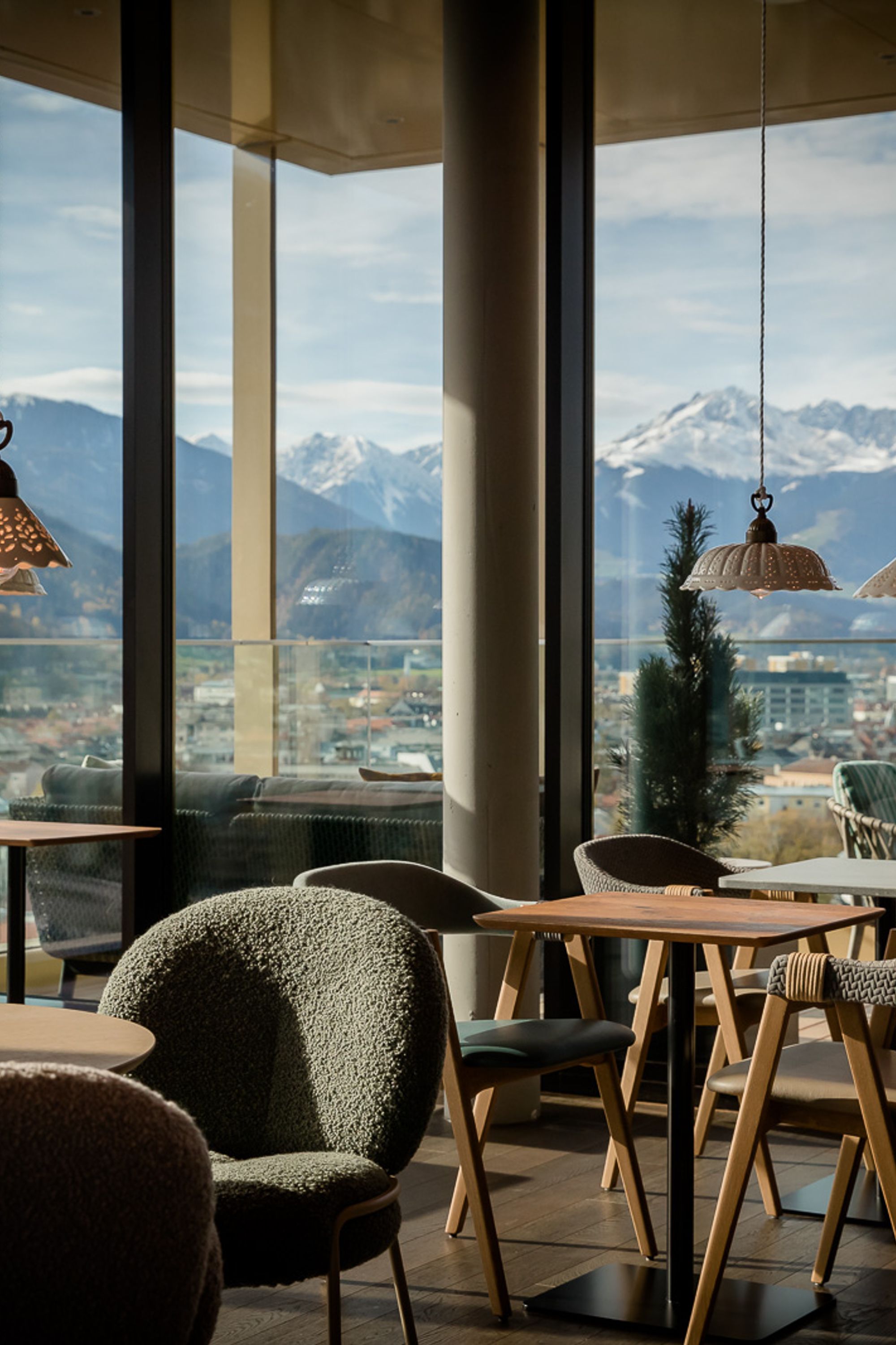 Designhotel Innsbruck Motel One Lounge mit Sitzgelegenheiten und bodentiefen Fenstern mit Ausblick auf die Berge