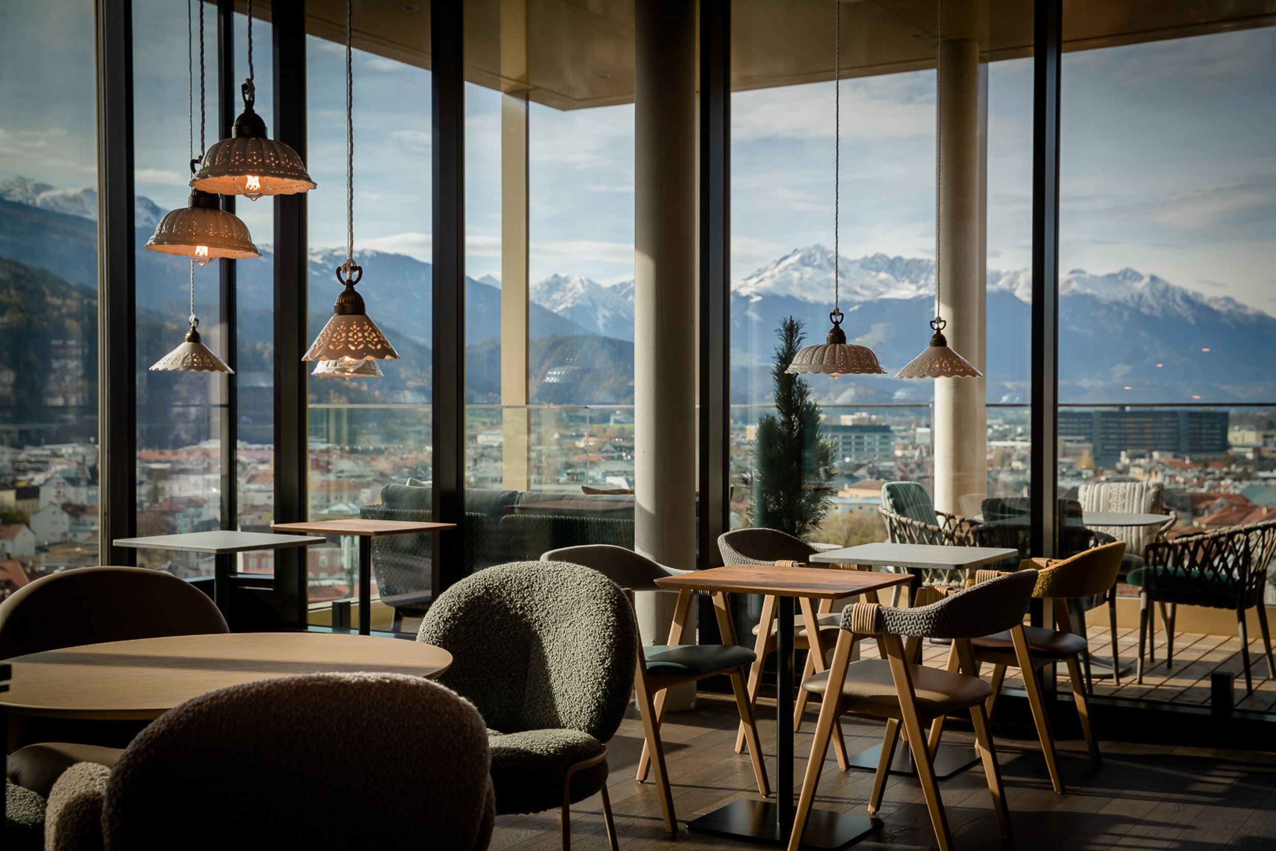 Designhotel Innsbruck Motel One Lounge mit Sitzgelegenheiten und bodentiefen Fenstern mit Ausblick auf die Berge