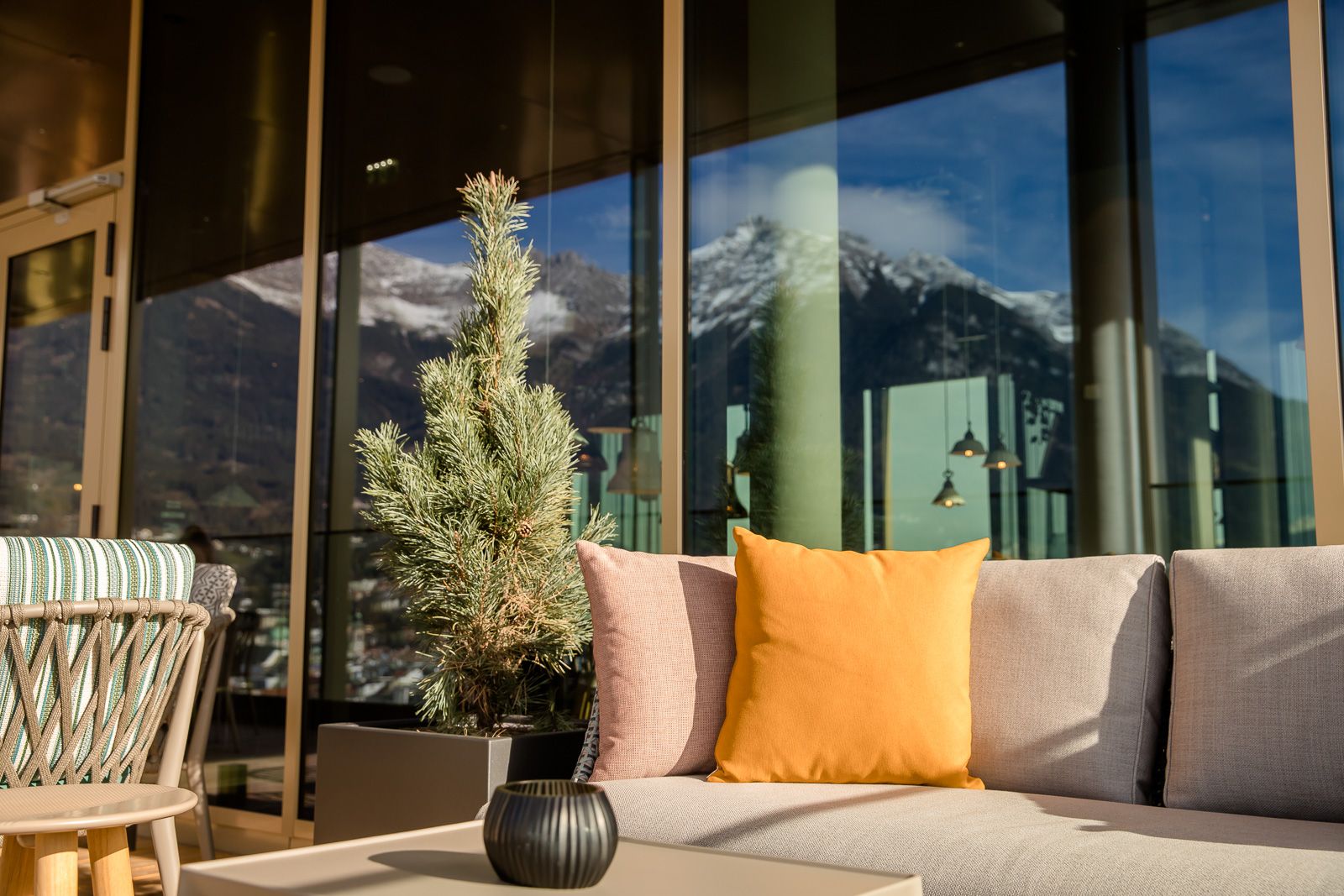 Designhotel Innsbruck Motel One Terrasse mit Sitzgelgenheiten und Spiegelung der Berge in der Fensterscheibe
