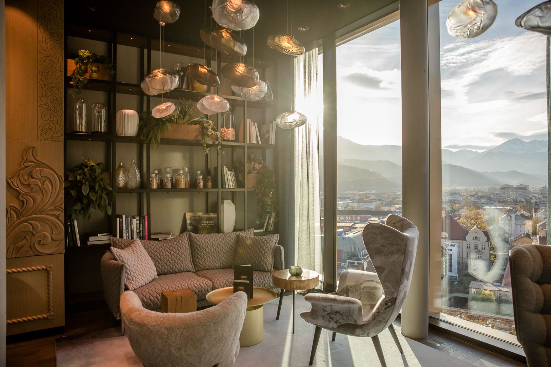 Designhotel Innsbruck Motel One lichtdurchflutete Lounge mit Sesseln vor bodentiefer Fensterfront